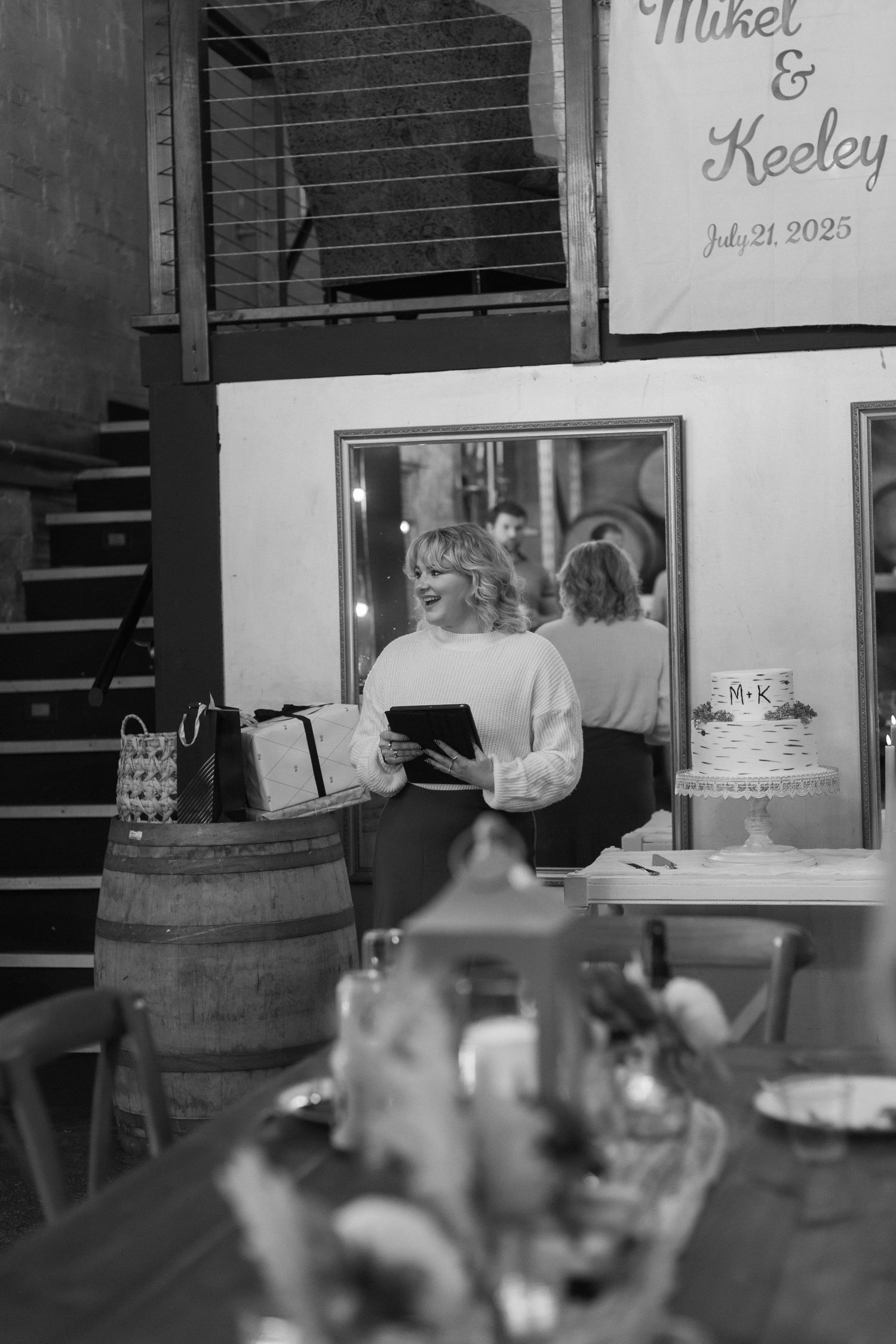 Wedding reception setup with rustic barrels and a sign visible in the background.