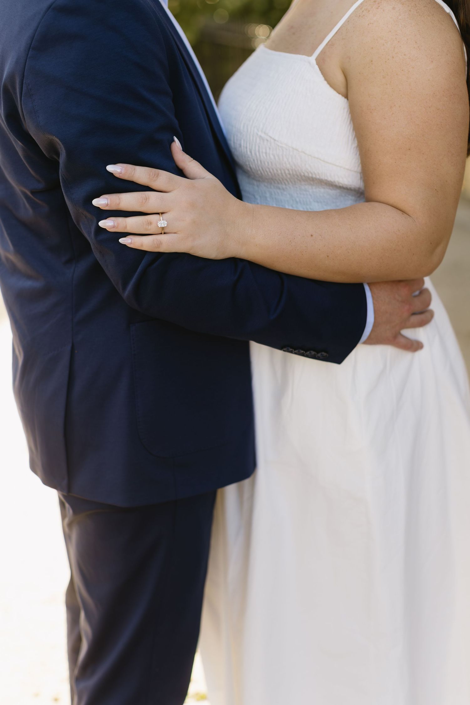 A couple in formal wedding attire stands close together during an intimate outdoor photo session.