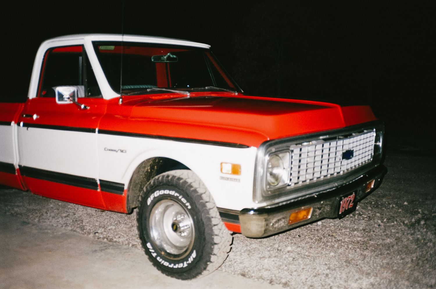 Vintage red pickup truck photographed at night with dramatic lighting.