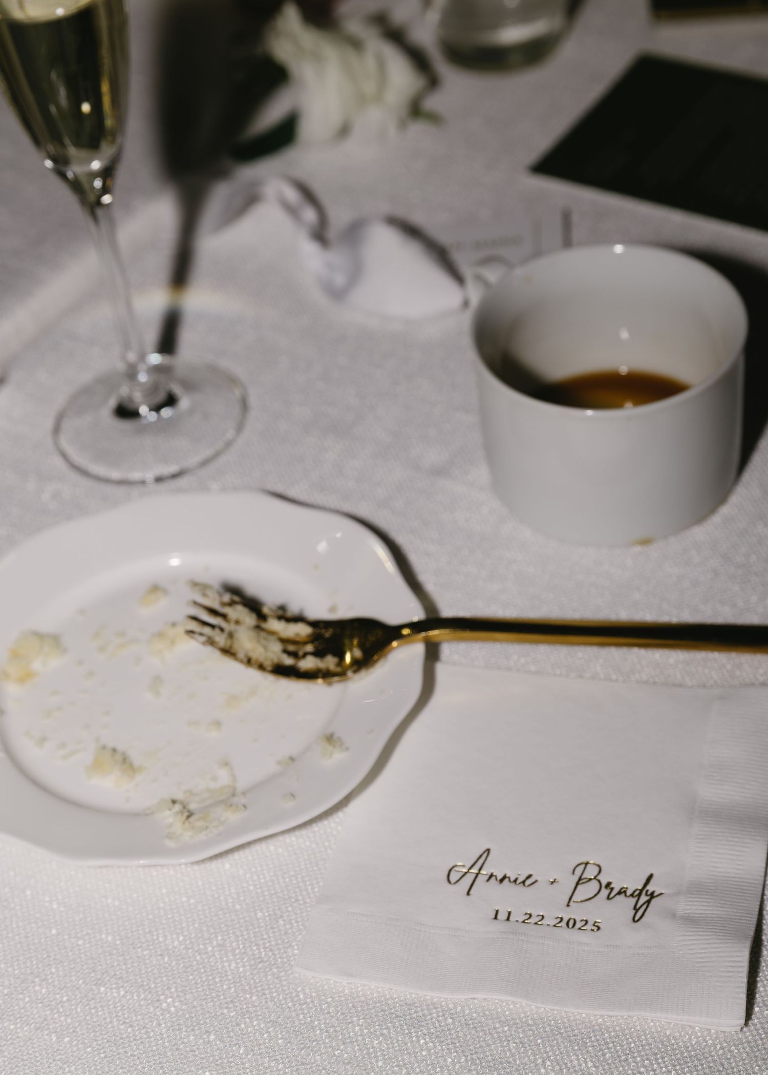Empty plates and glasses on white tablecloth with wedding place cards.
