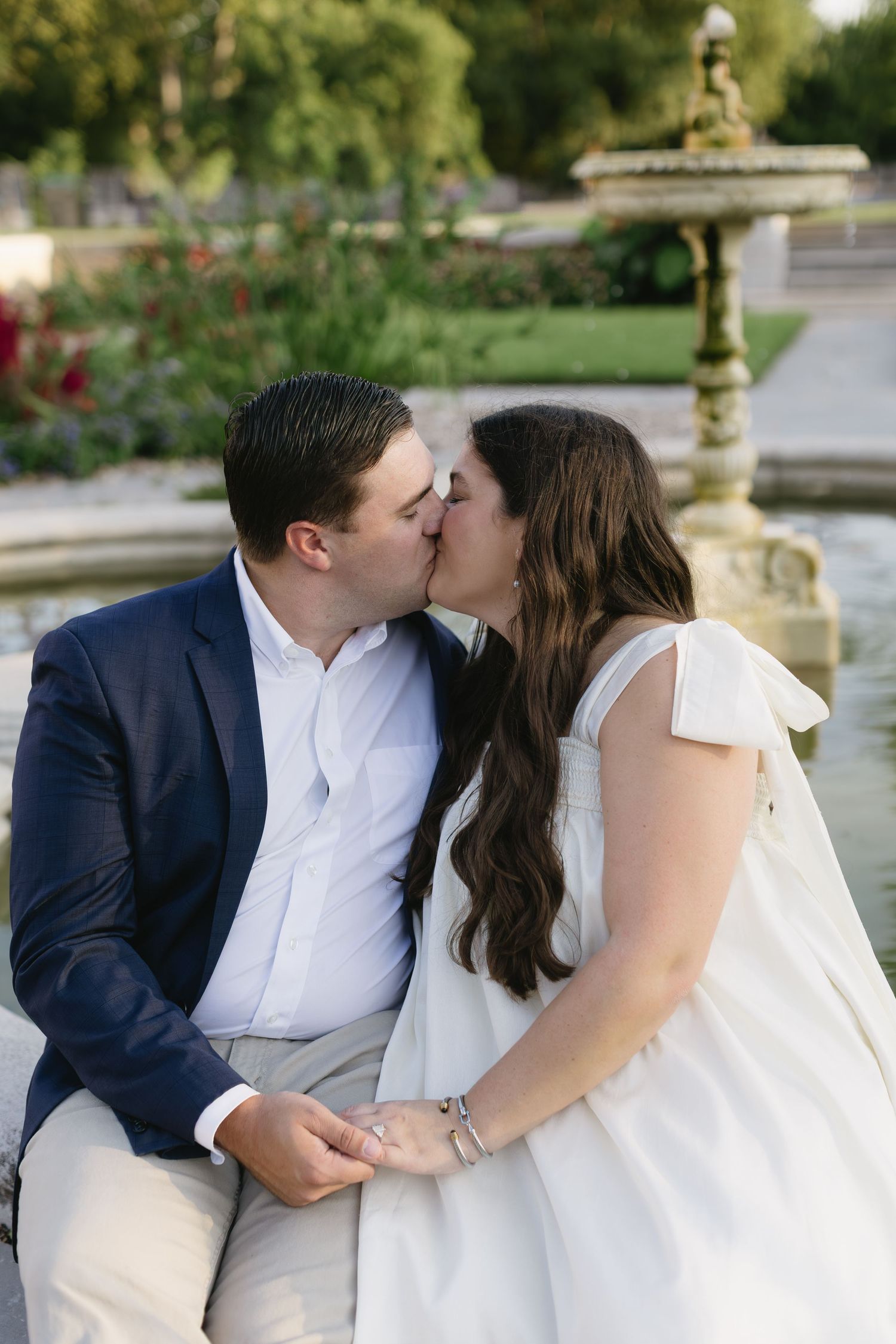 Wedding couple sharing tender moments in a beautiful garden setting with ornate architecture.