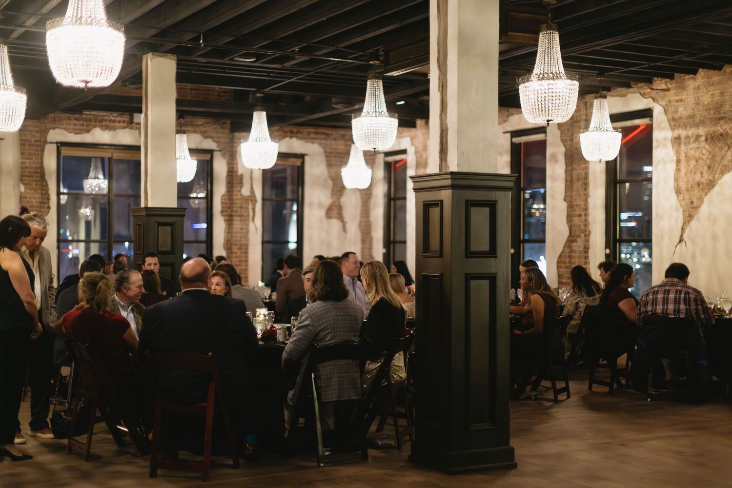 Panoramic view of an industrial-style restaurant interior with hanging lights and exposed brick.