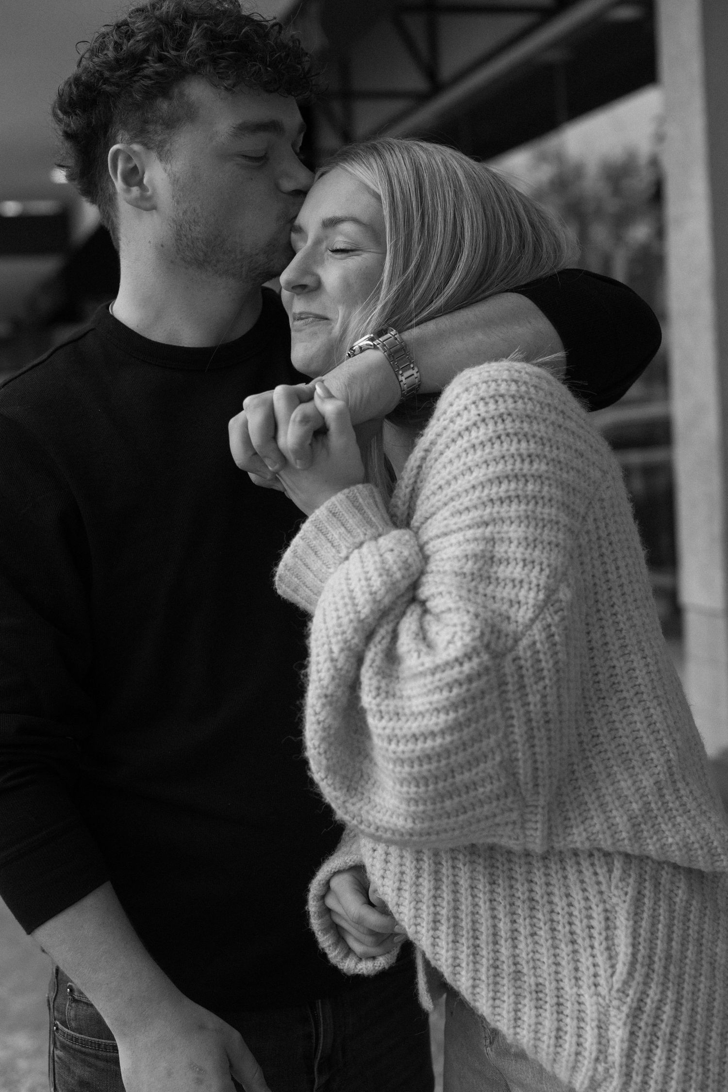 Black and white photo of couple in cozy sweaters sharing an intimate moment.