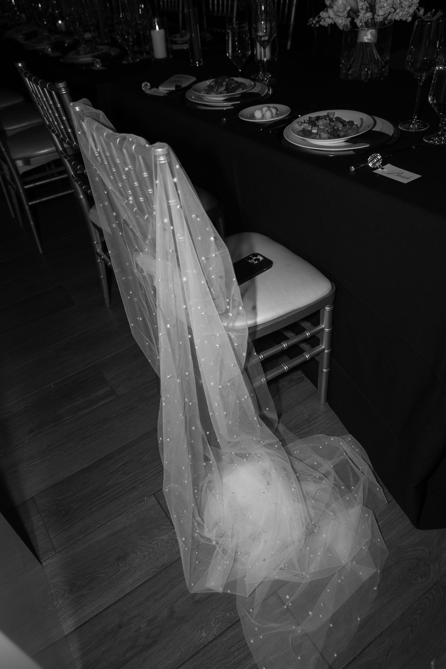 Delicate tulle veil draped over a white chair at an elegant wedding reception table.