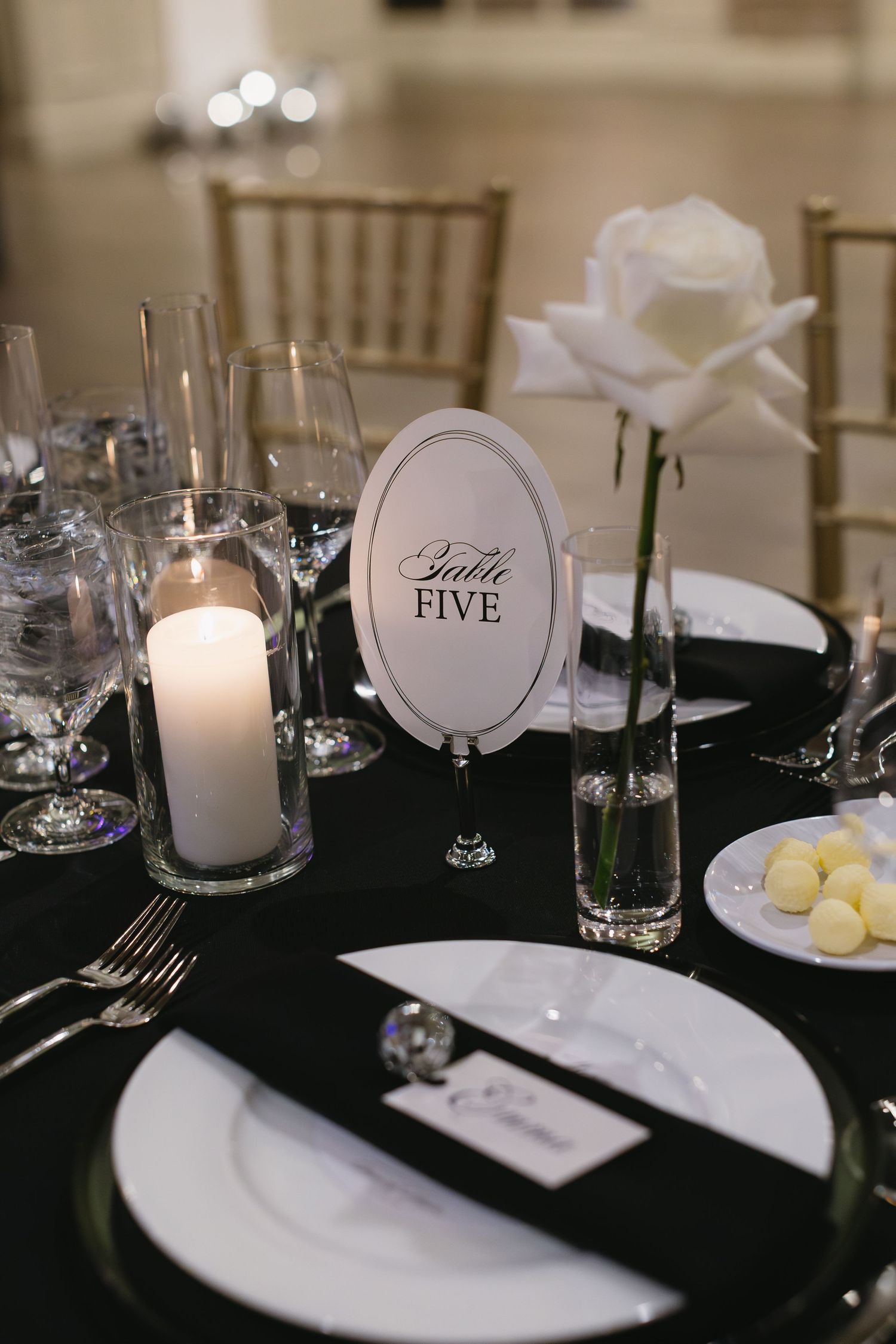 Elegant black and white table settings with candles and place cards.