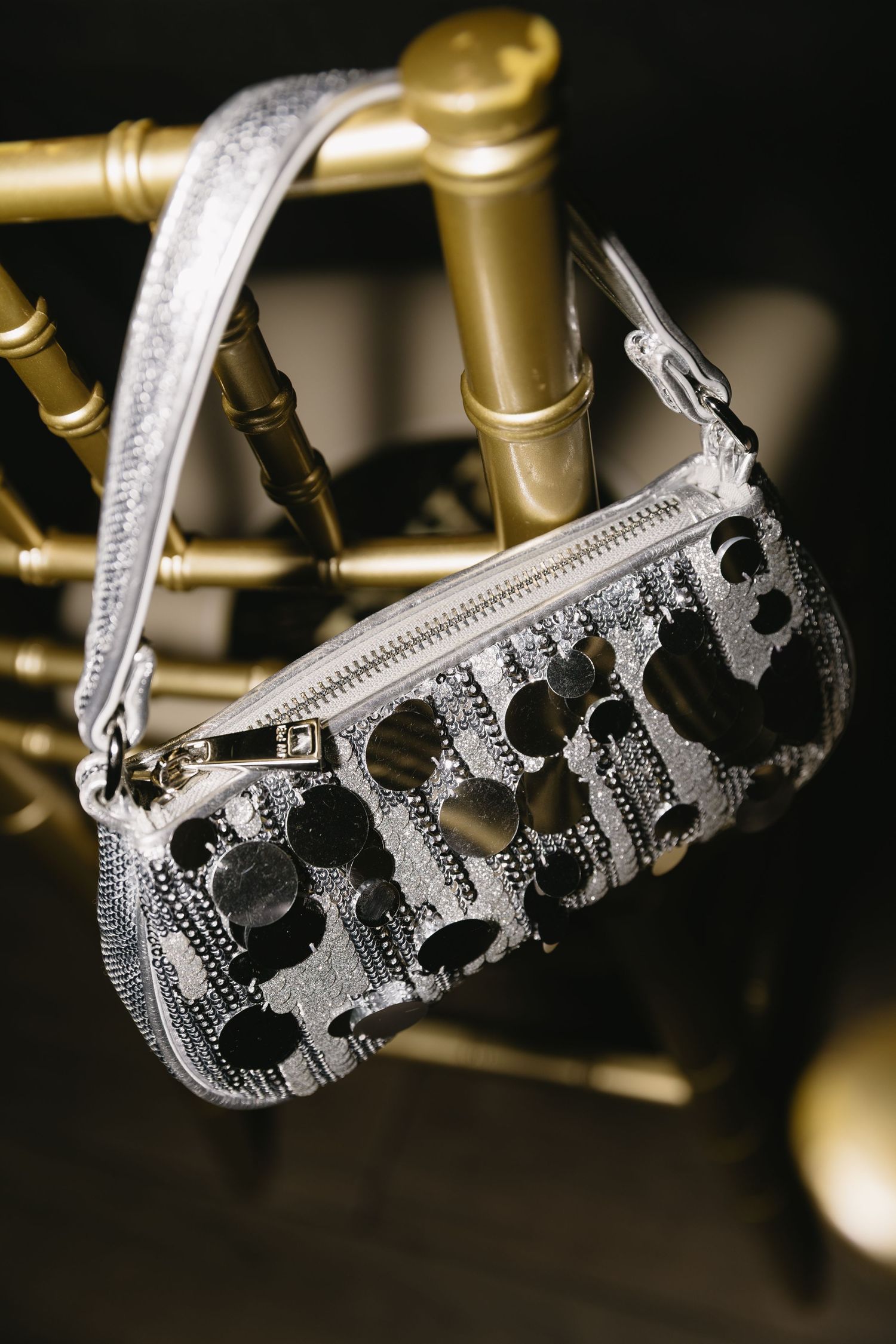 Close-up view of ornate silver tiaras with intricate details displayed on gold stands.