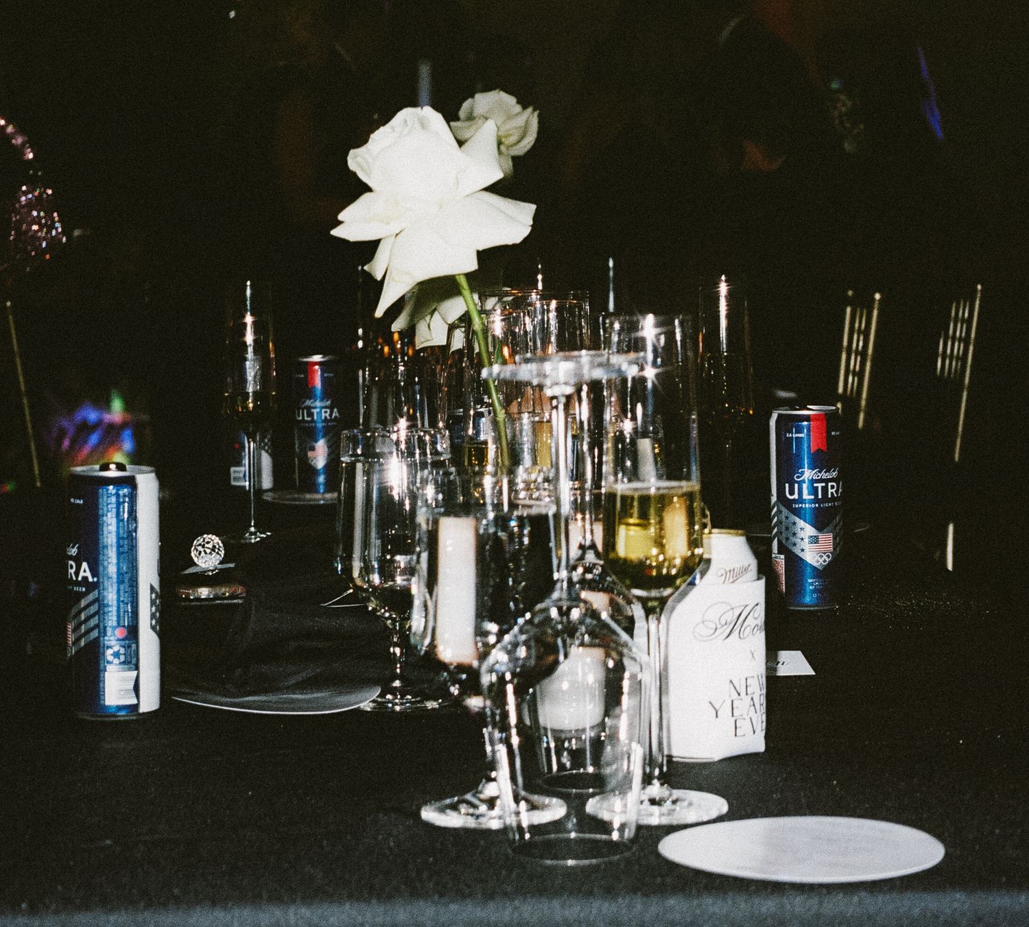 Bar setup with various liquor bottles and glassware at a dark reception venue.