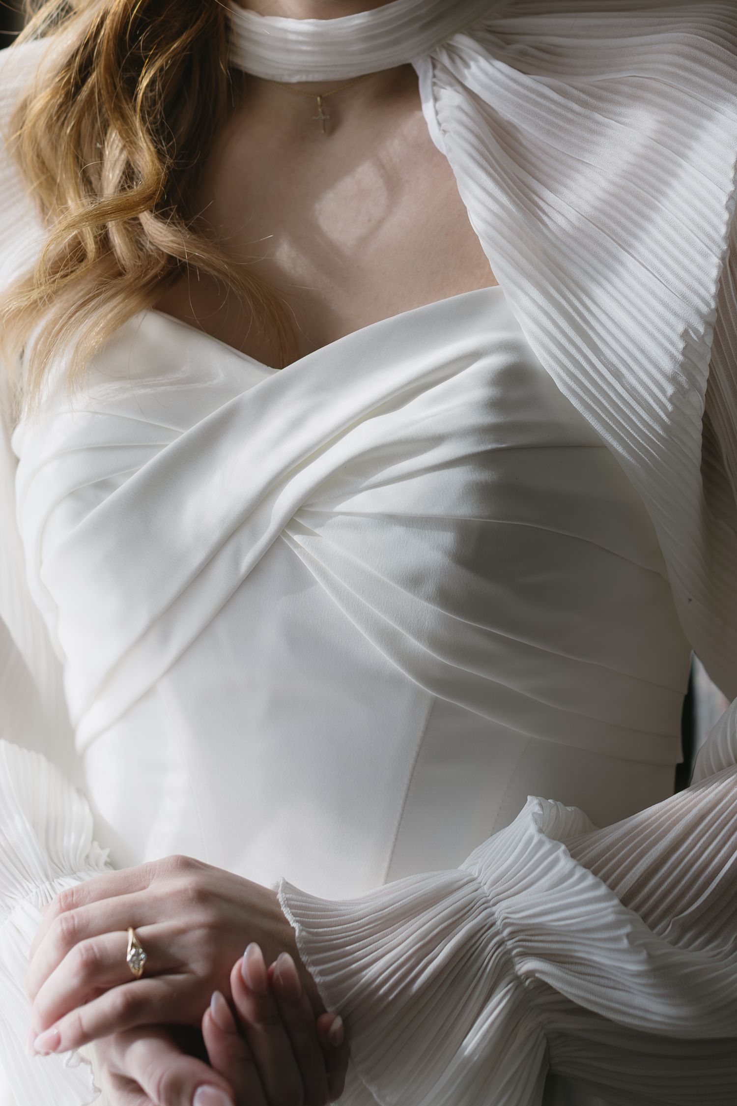 Detail shots of pleated white wedding dress bodice and delicate fabric texture.