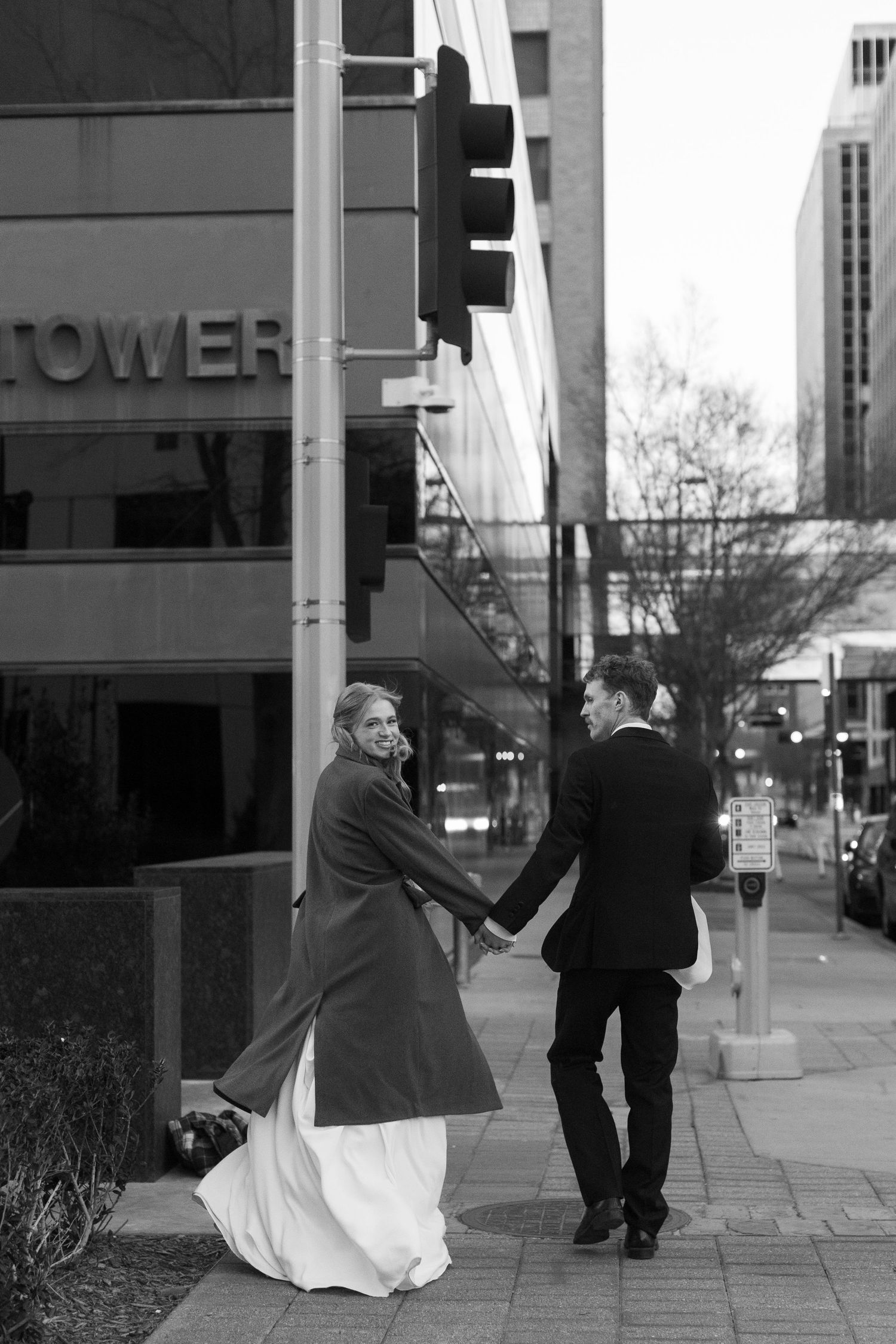 Black and white wedding photos of a couple dancing on a city sidewalk.