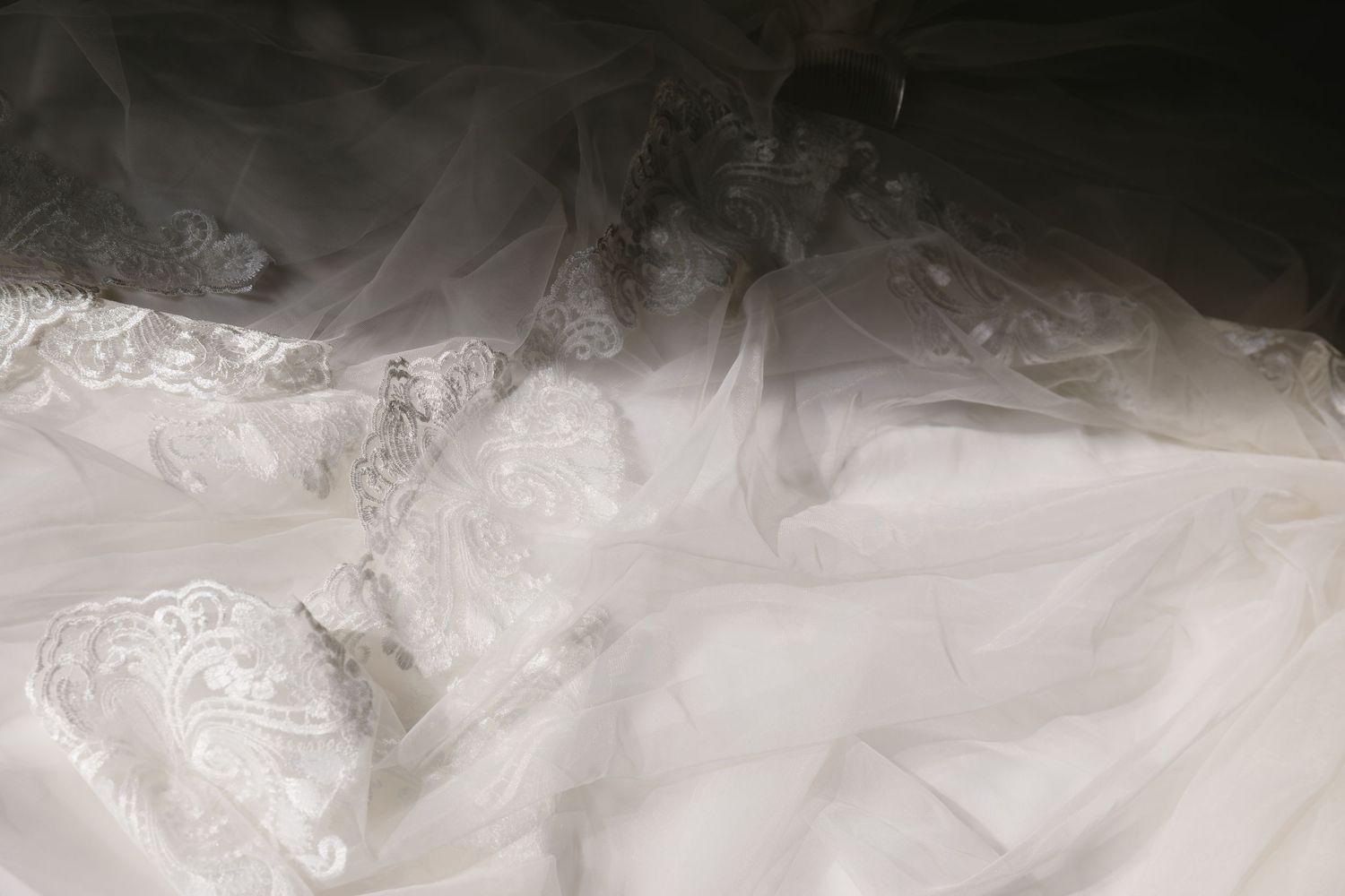 White tulle fabric creates a soft, ethereal texture with delicate folds and flowing layers against a dark background.