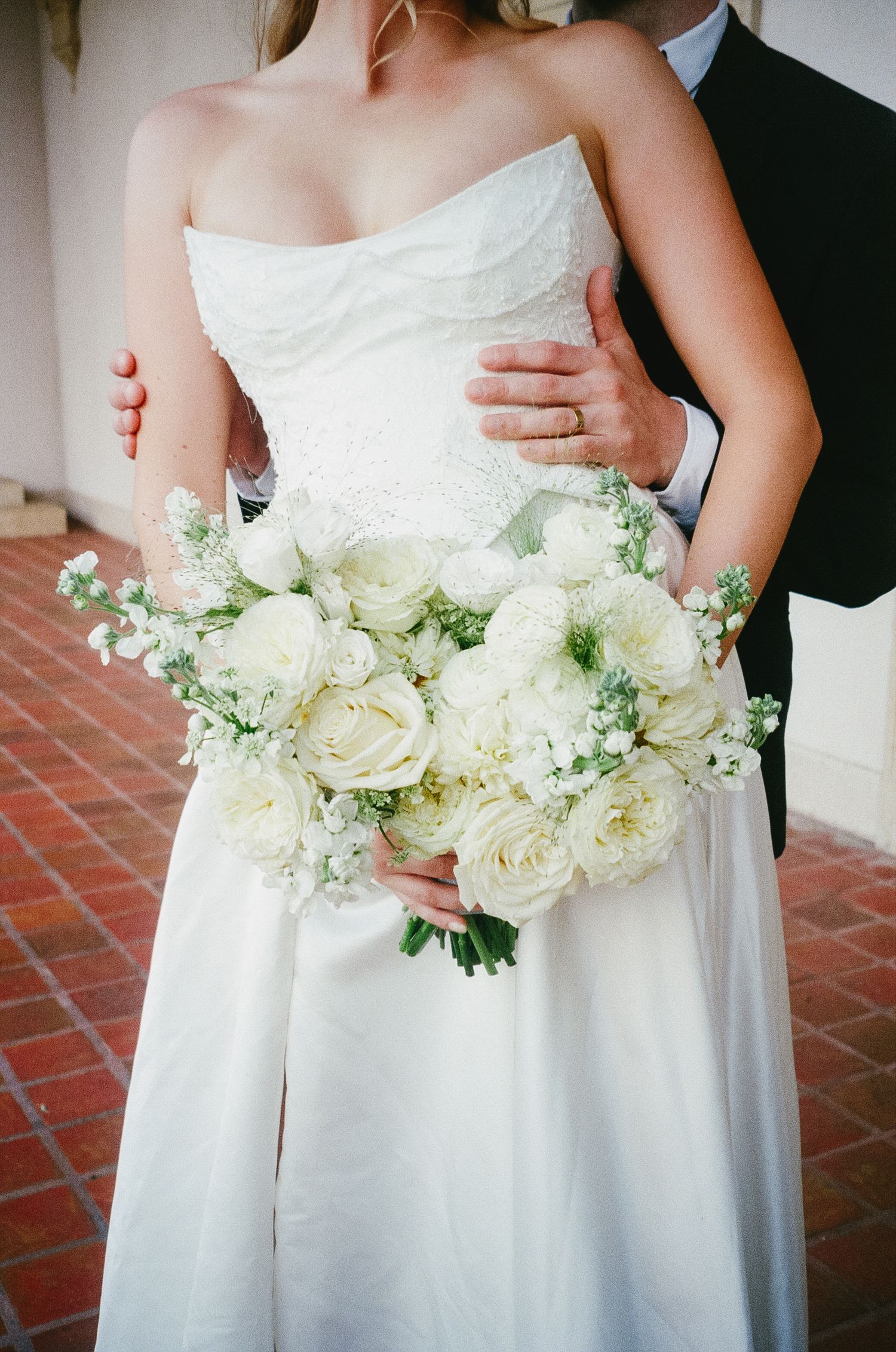 A romantic wedding scene showing a white bridal gown and elegant bouquet of white roses and baby's breath flowers.