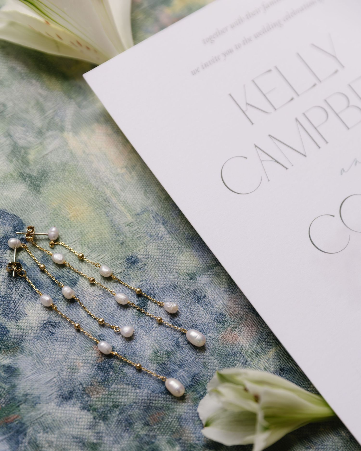 Pearl hair accessories and white paper invitations create an elegant wedding detail arrangement.