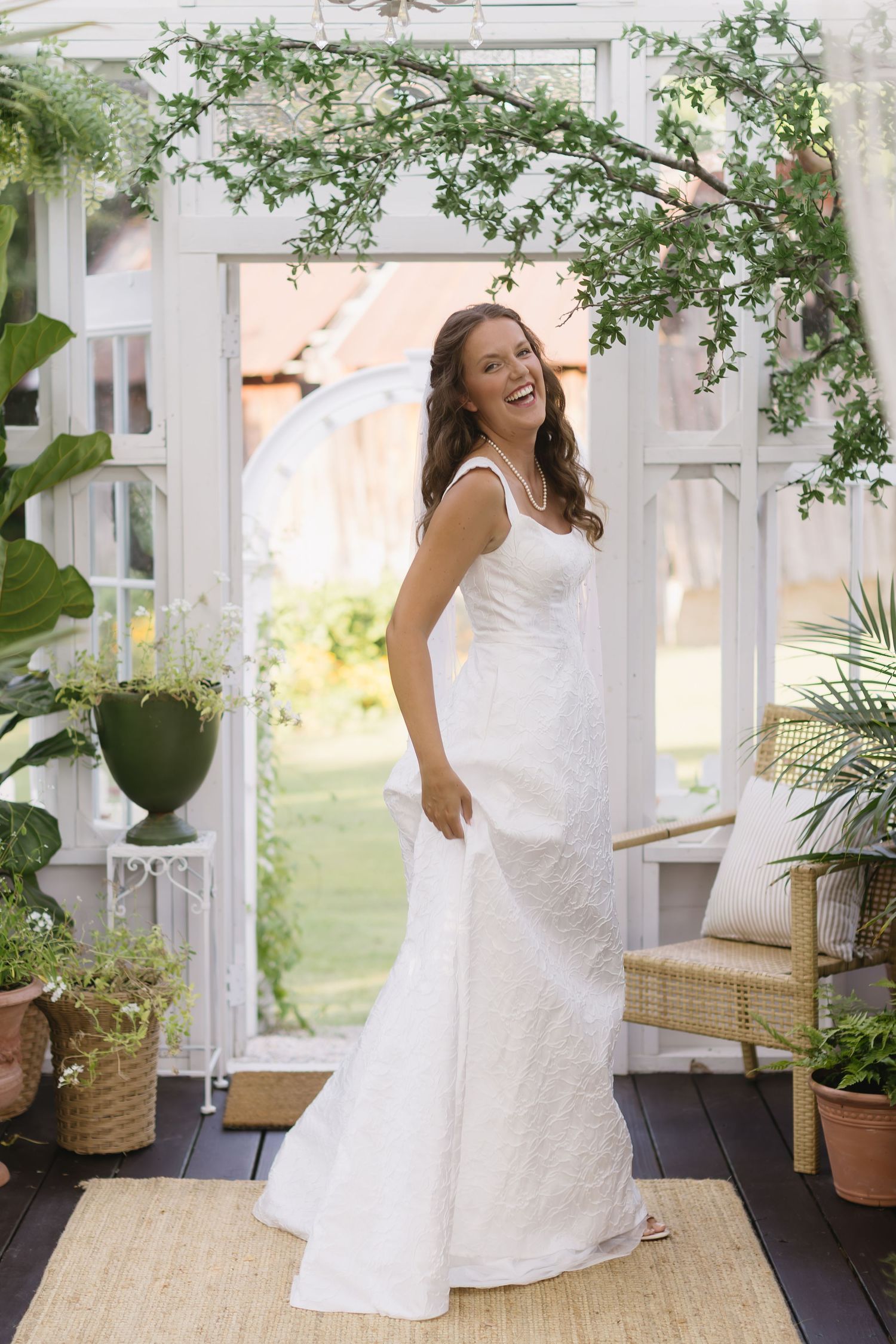 White wedding dress twirling on an outdoor covered porch with potted plants and garden views.