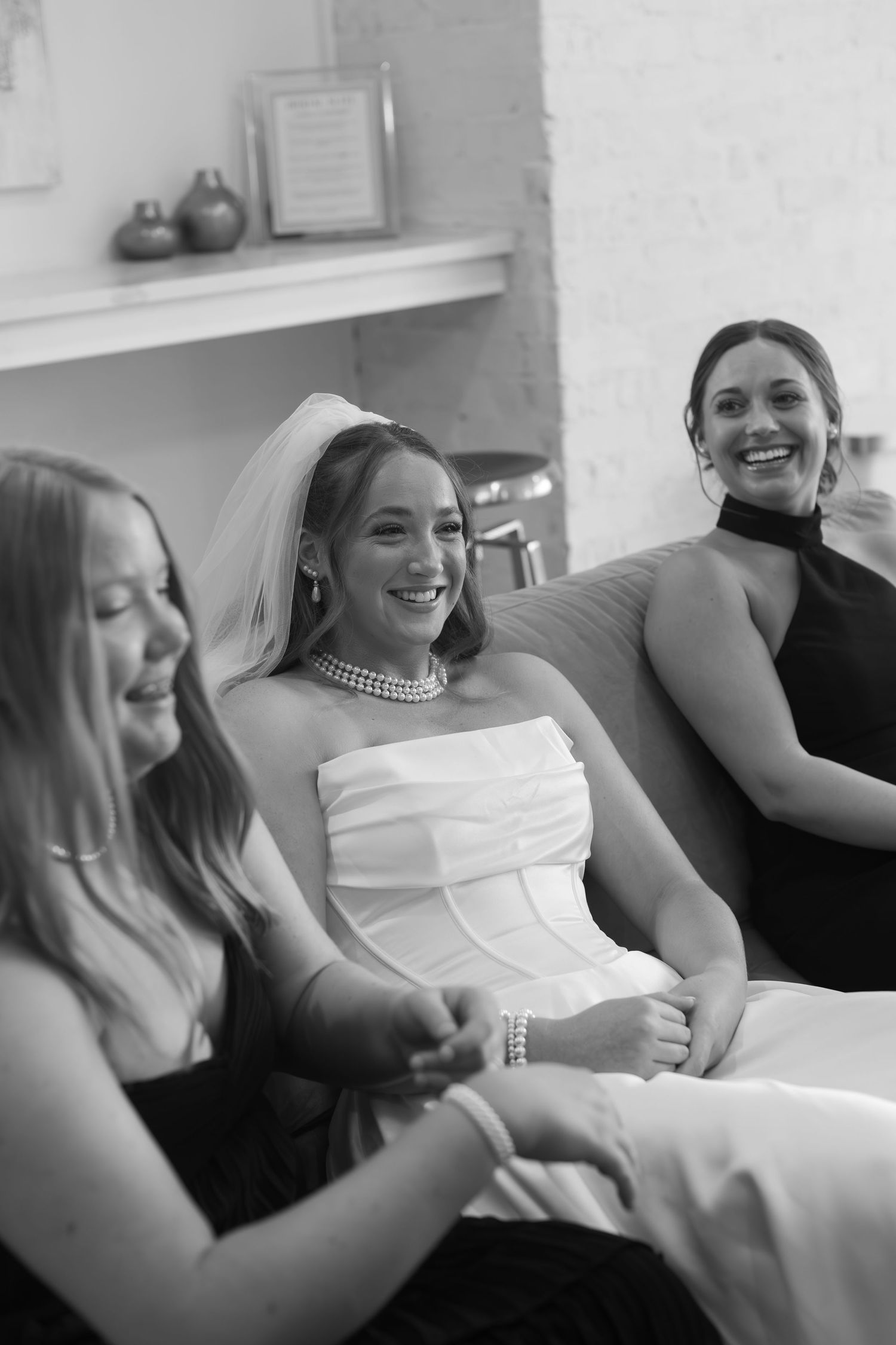 Wedding party members relaxing on a couch wearing formal attire during preparations.
