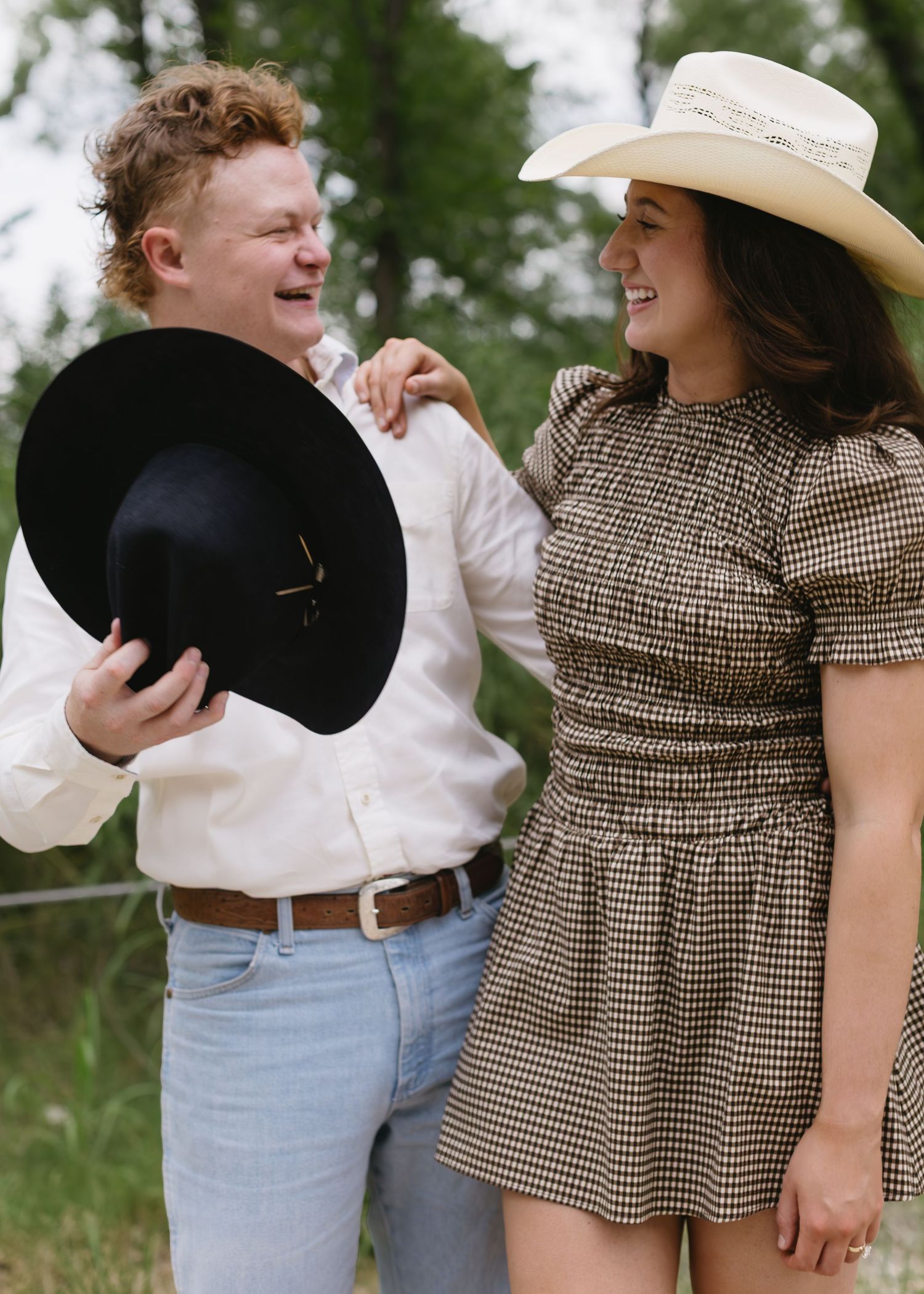 Couple in casual western wear share playful moments together outdoors.