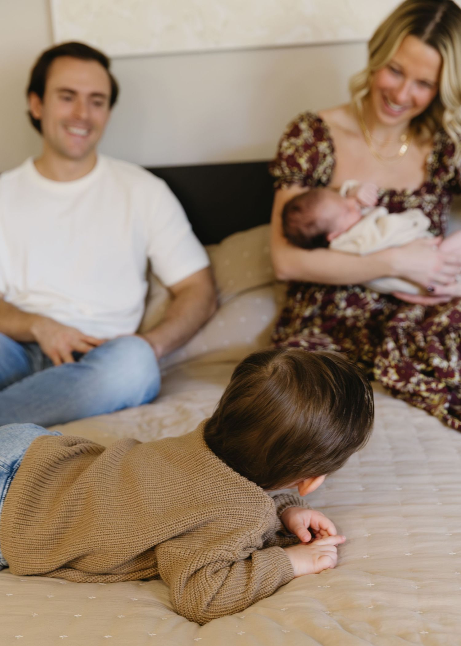 Family lounging together on bed in casual attire.