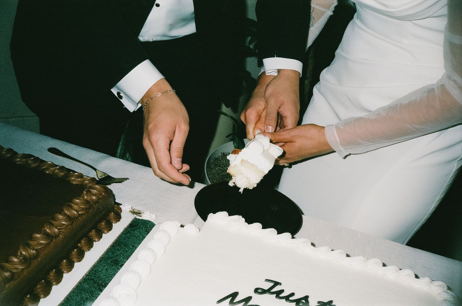 Chef decorating a white wedding cake with delicate piping and floral details in a professional kitchen.