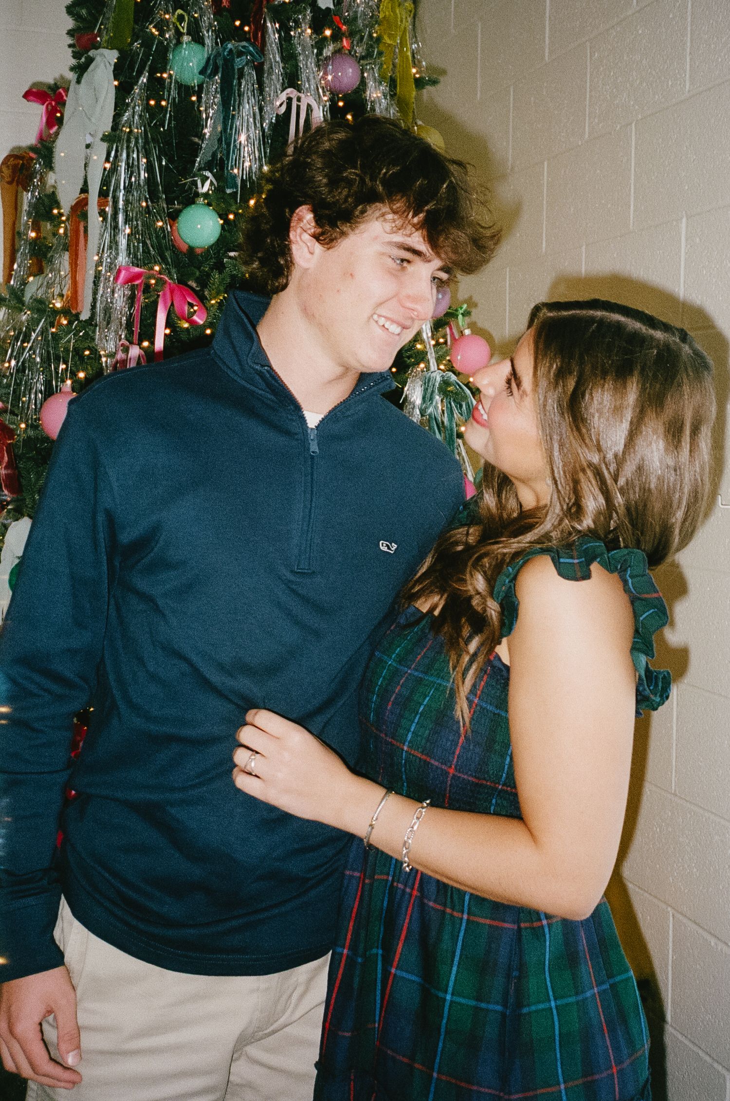 Holiday party photos showing a couple sharing sweet moments in front of a decorated Christmas tree.