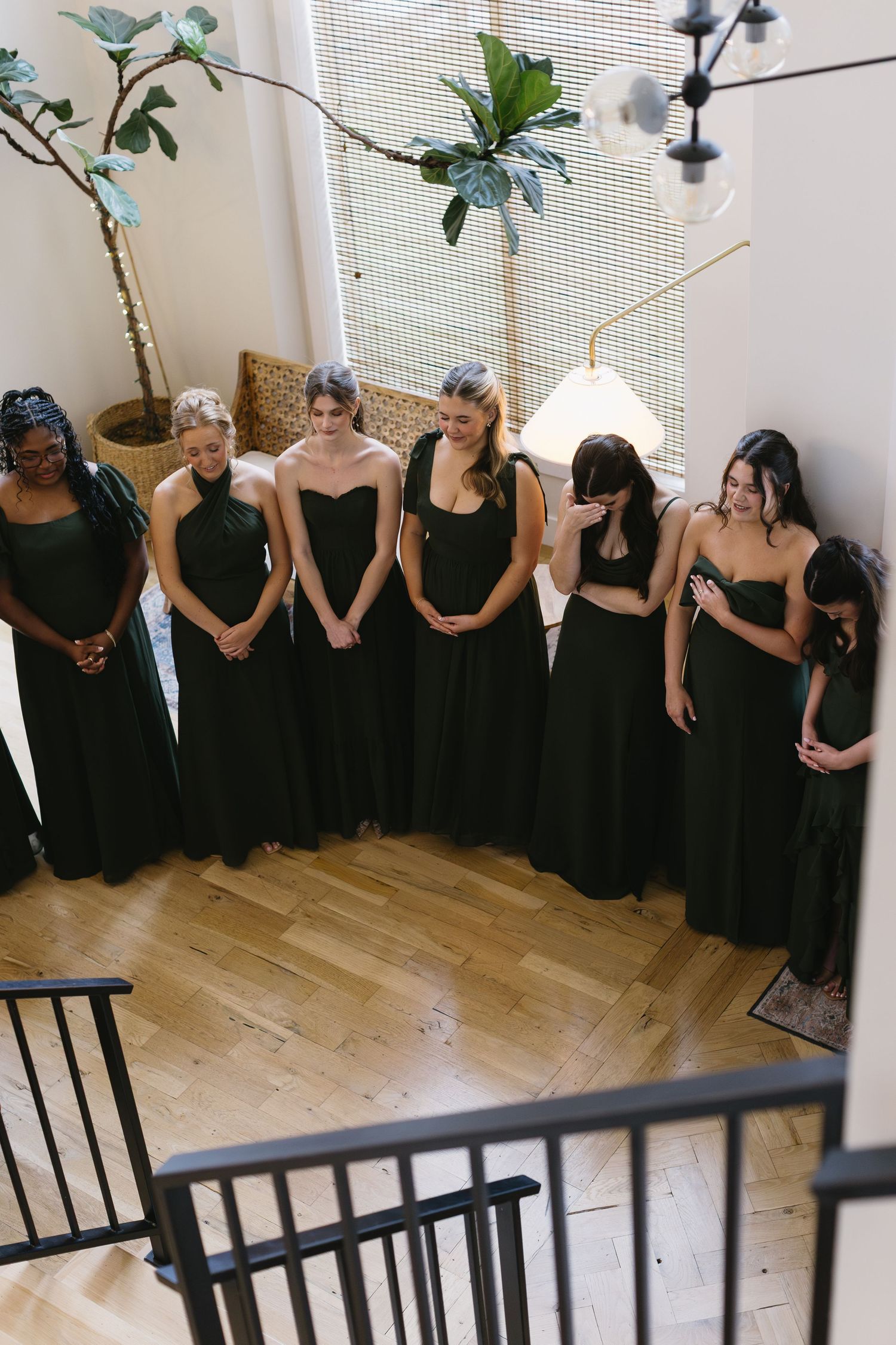A group of bridesmaids in matching black dresses stand together in an indoor setting.