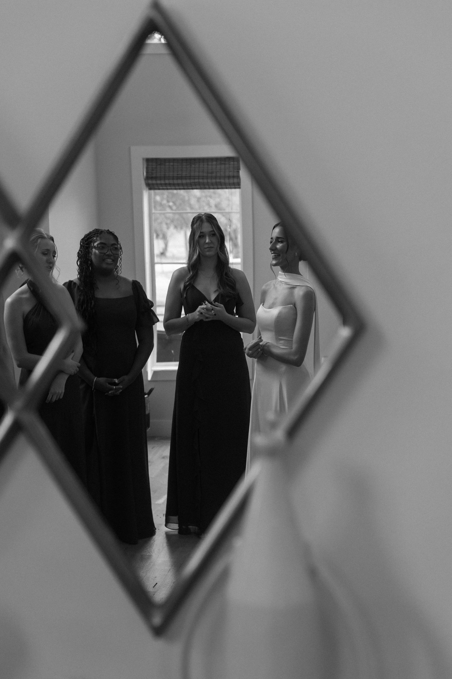 A mirror reflection captures a group wearing formal attire during wedding preparations.