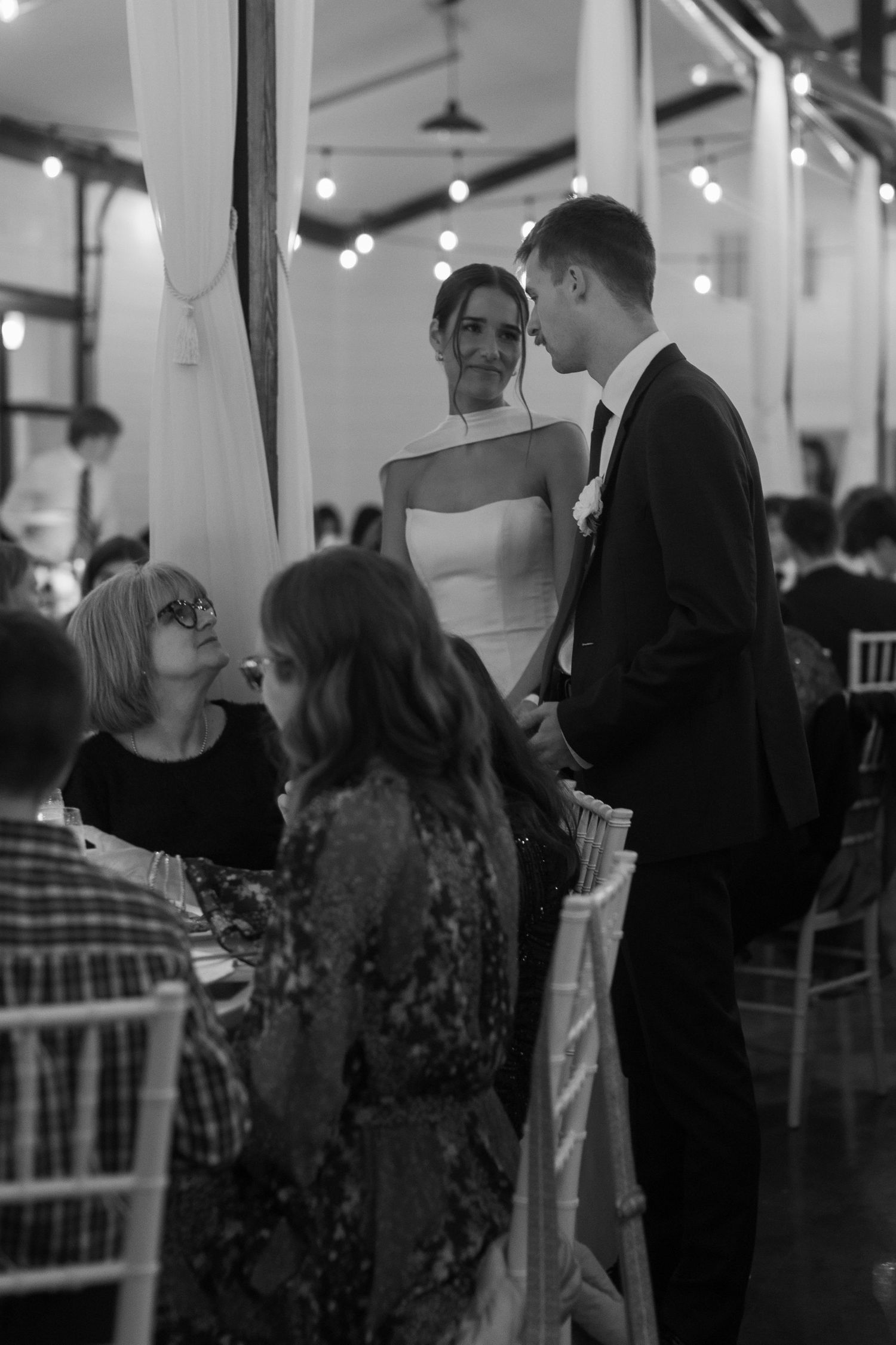 Indoor wedding reception with guests mingling under ambient lighting.
