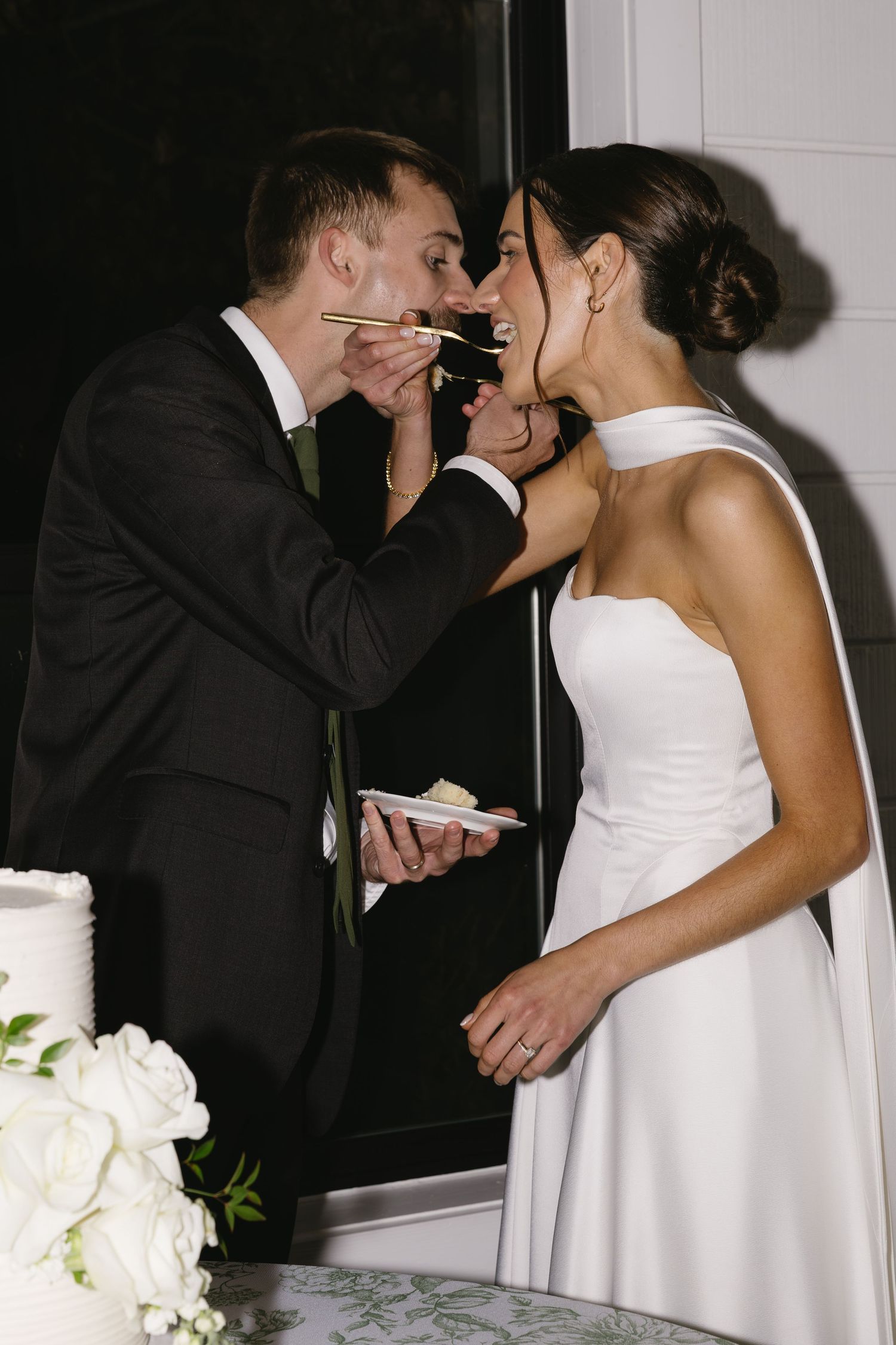 Intimate black and white photo series of newlyweds sharing moments by their wedding cake.