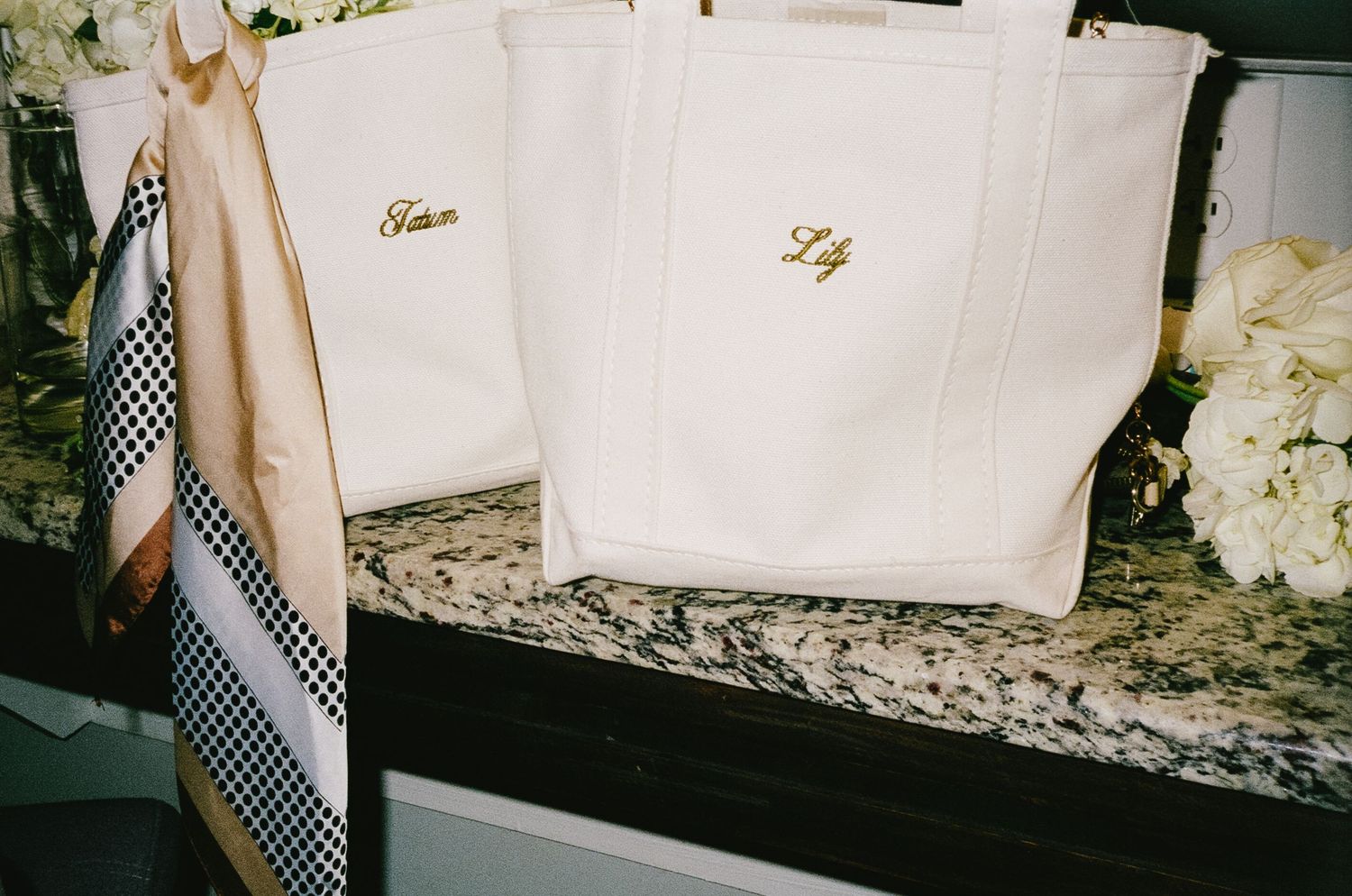 White personalized tote bags with gold monograms displayed on granite countertop.