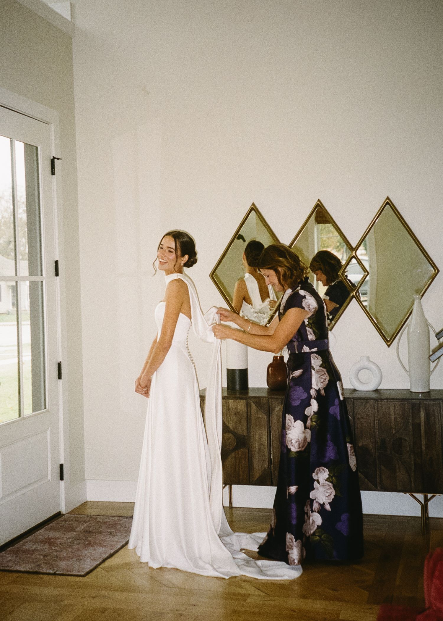 Bridal preparation room with mirrors and natural light showing wedding dress preparations.