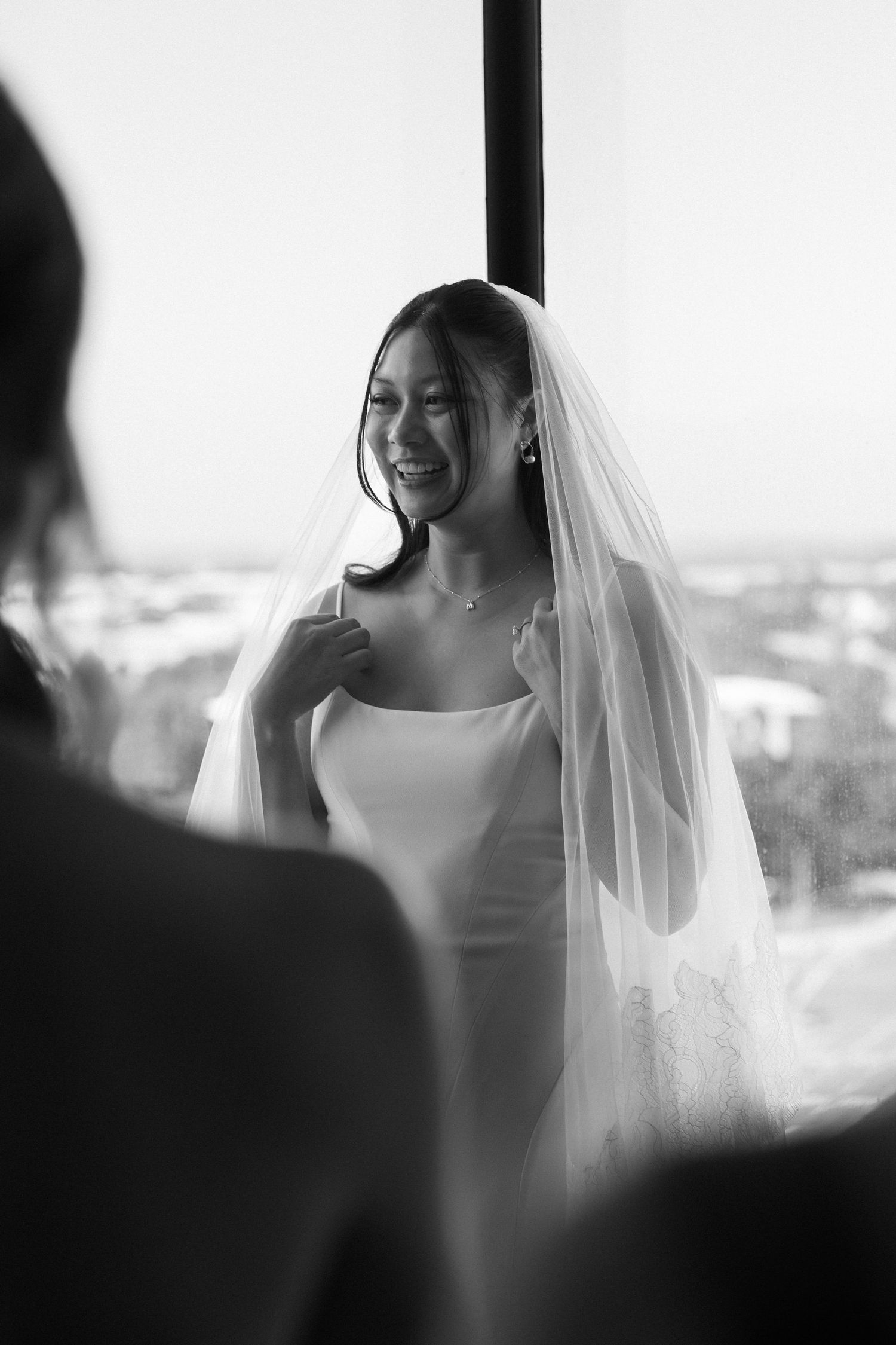 Artistic black and white sequence of a bride smiling in natural window light.