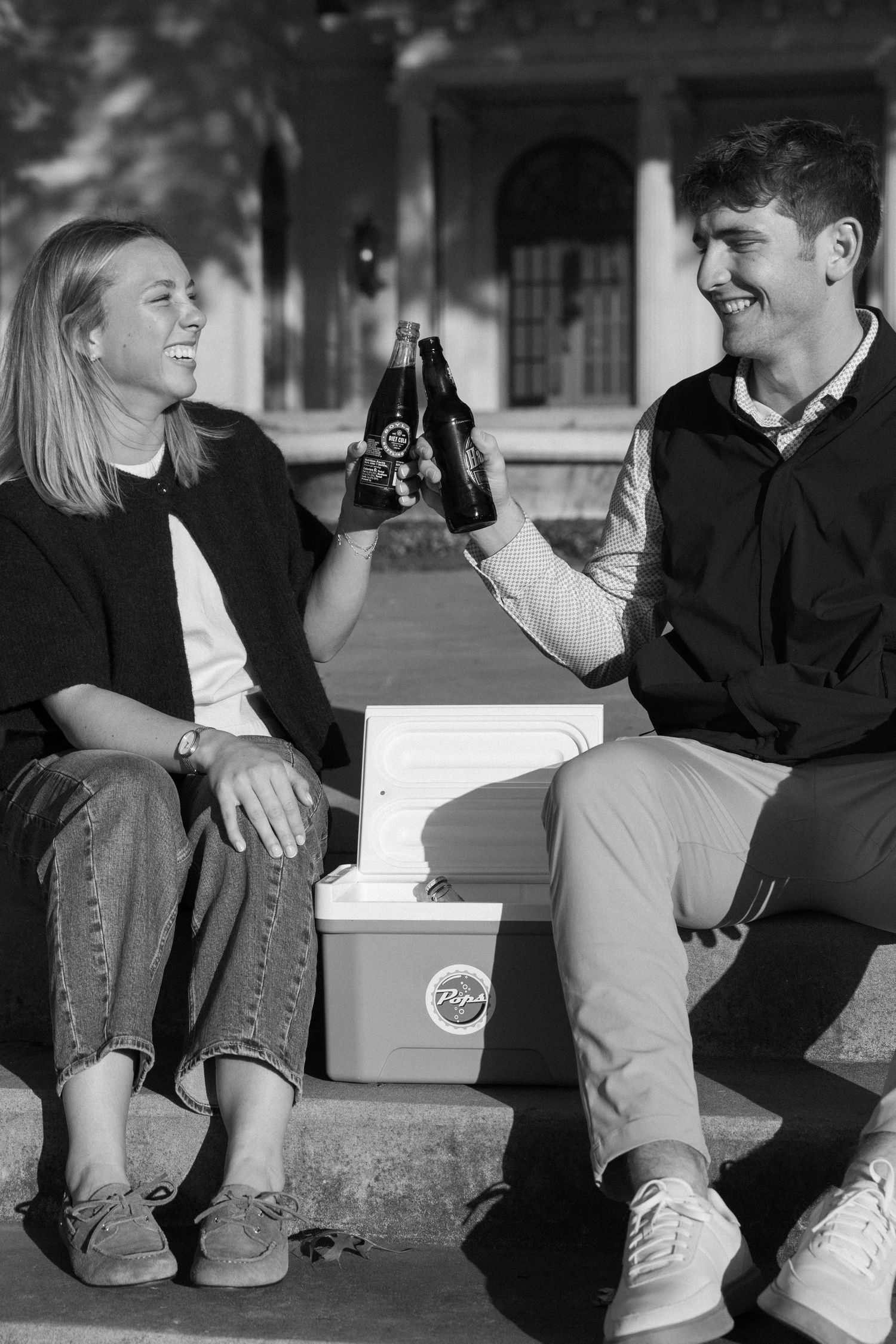 A black and white photo series showing a couple sitting and laughing together on stone steps.