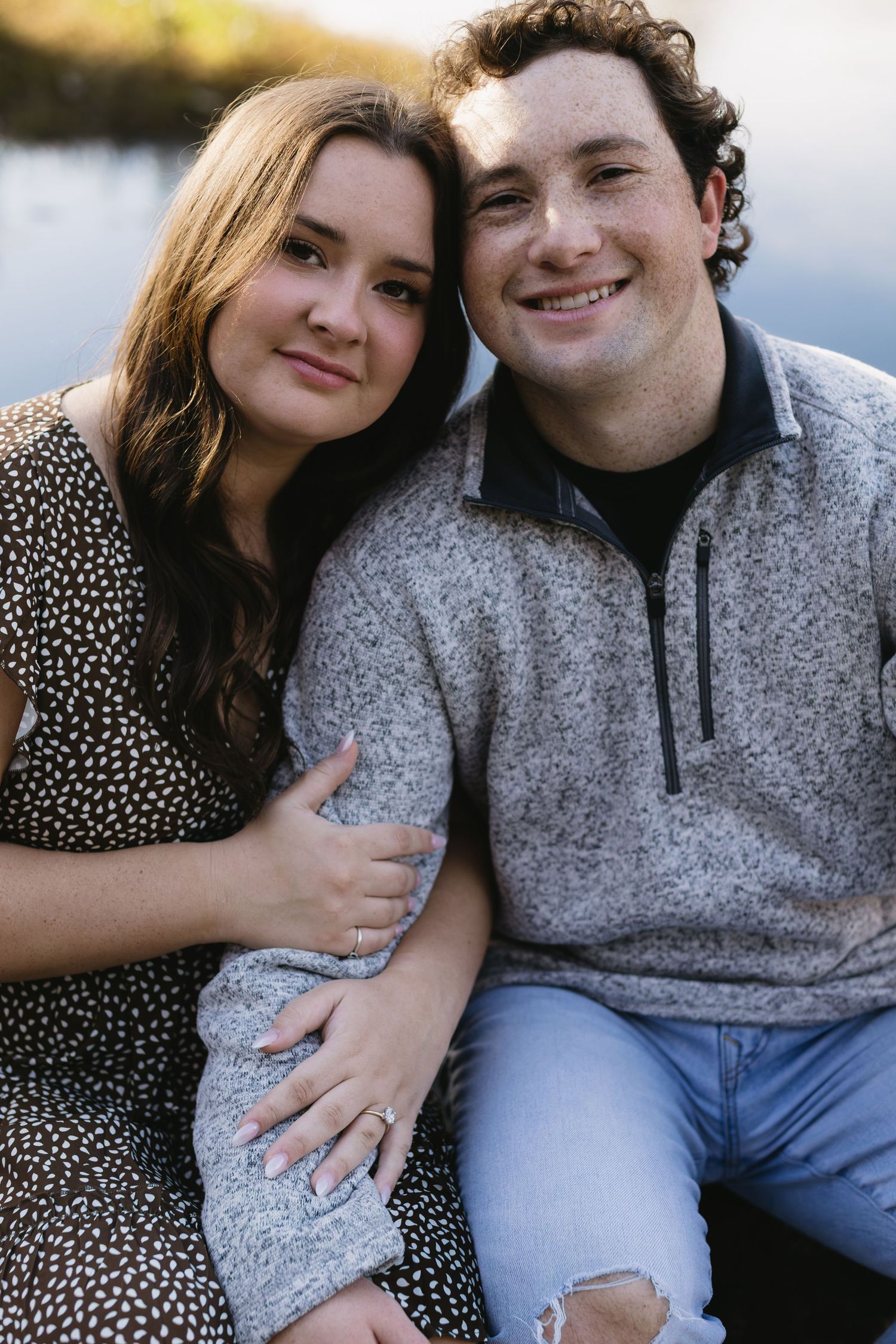 A couple in casual wear poses together outdoors during a romantic photoshoot session.