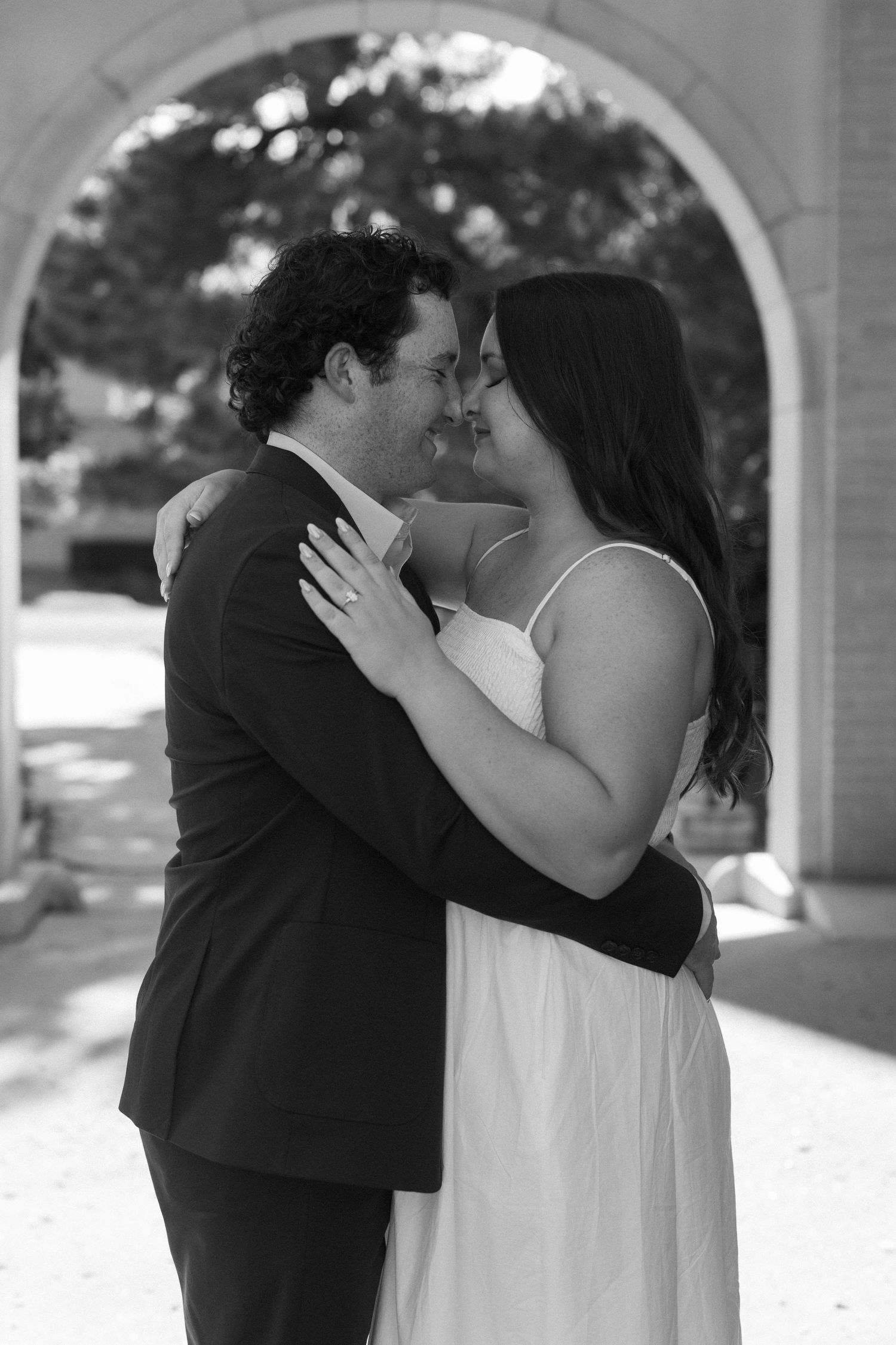 A romantic moment shared between a couple in formal attire under an archway.