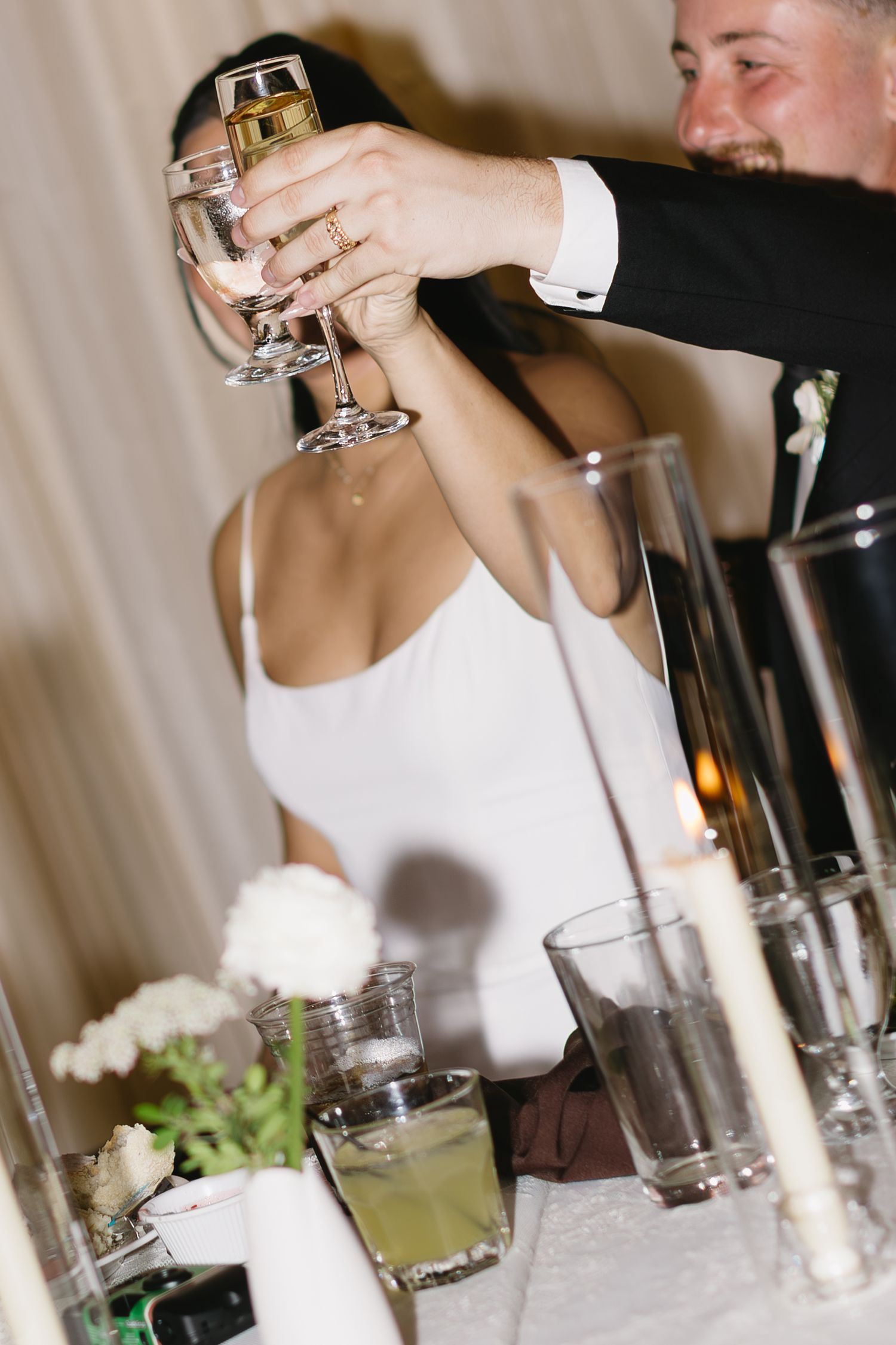Wedding guests raise glasses in a toast during an elegant reception celebration at a formal dinner.