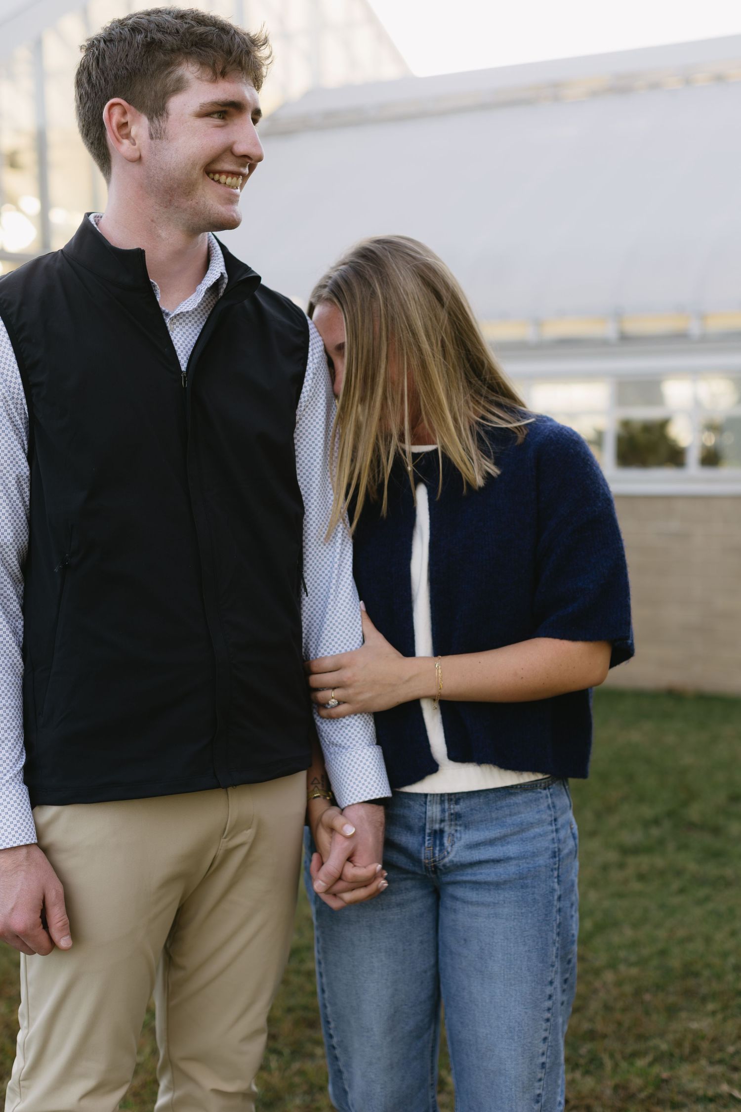 A romantic outdoor photoshoot showing a couple embracing and laughing together in casual fall attire.