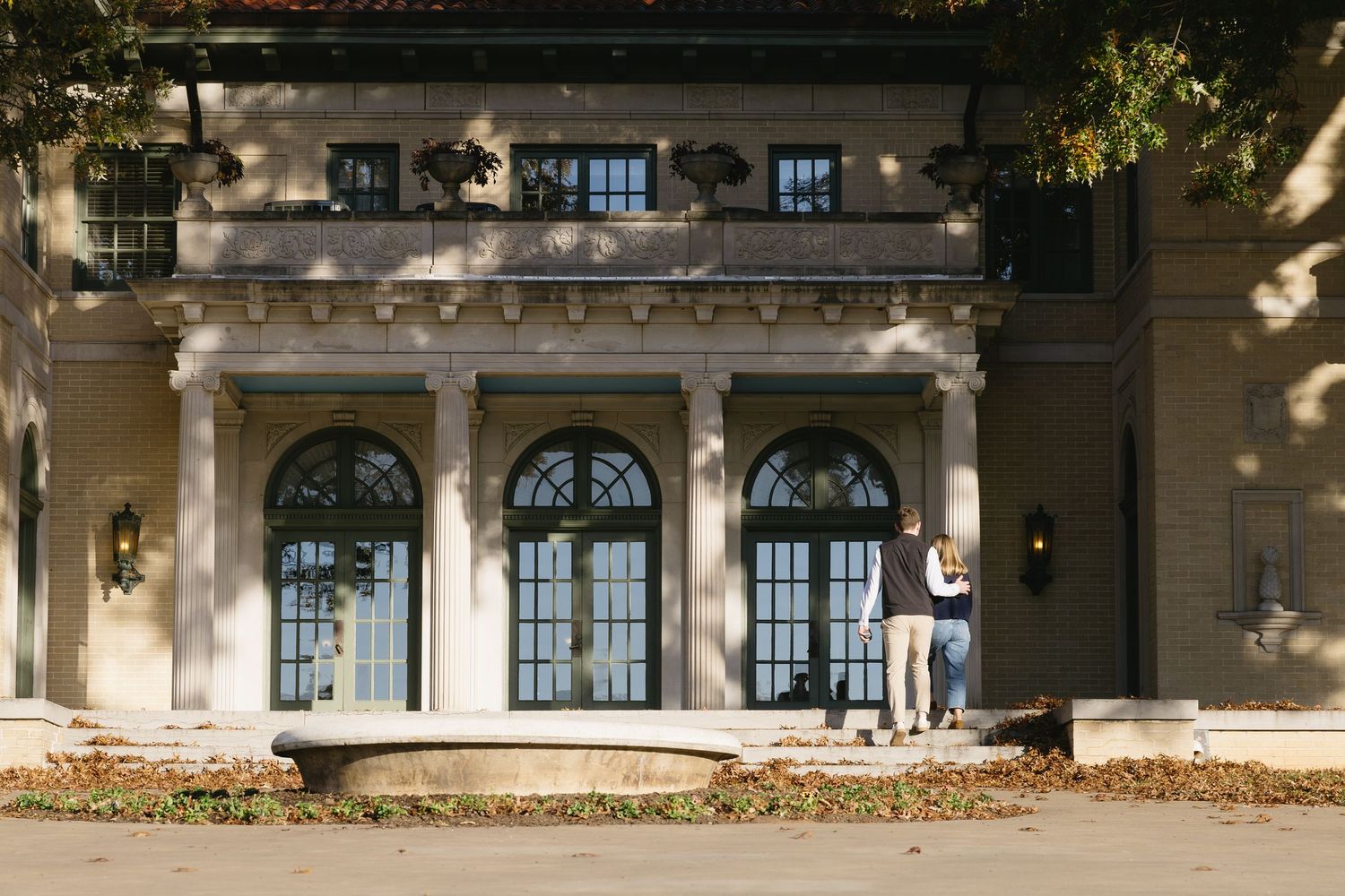 Exterior view of a classical building with columns and arched windows.