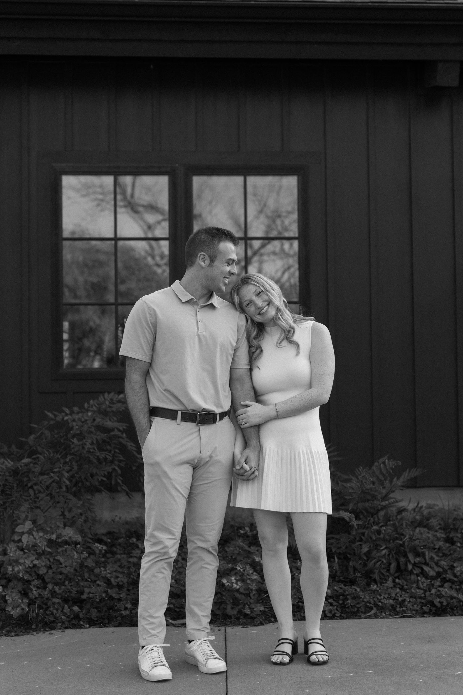 Black and white photo series of a couple in light clothing posing against a dark building.