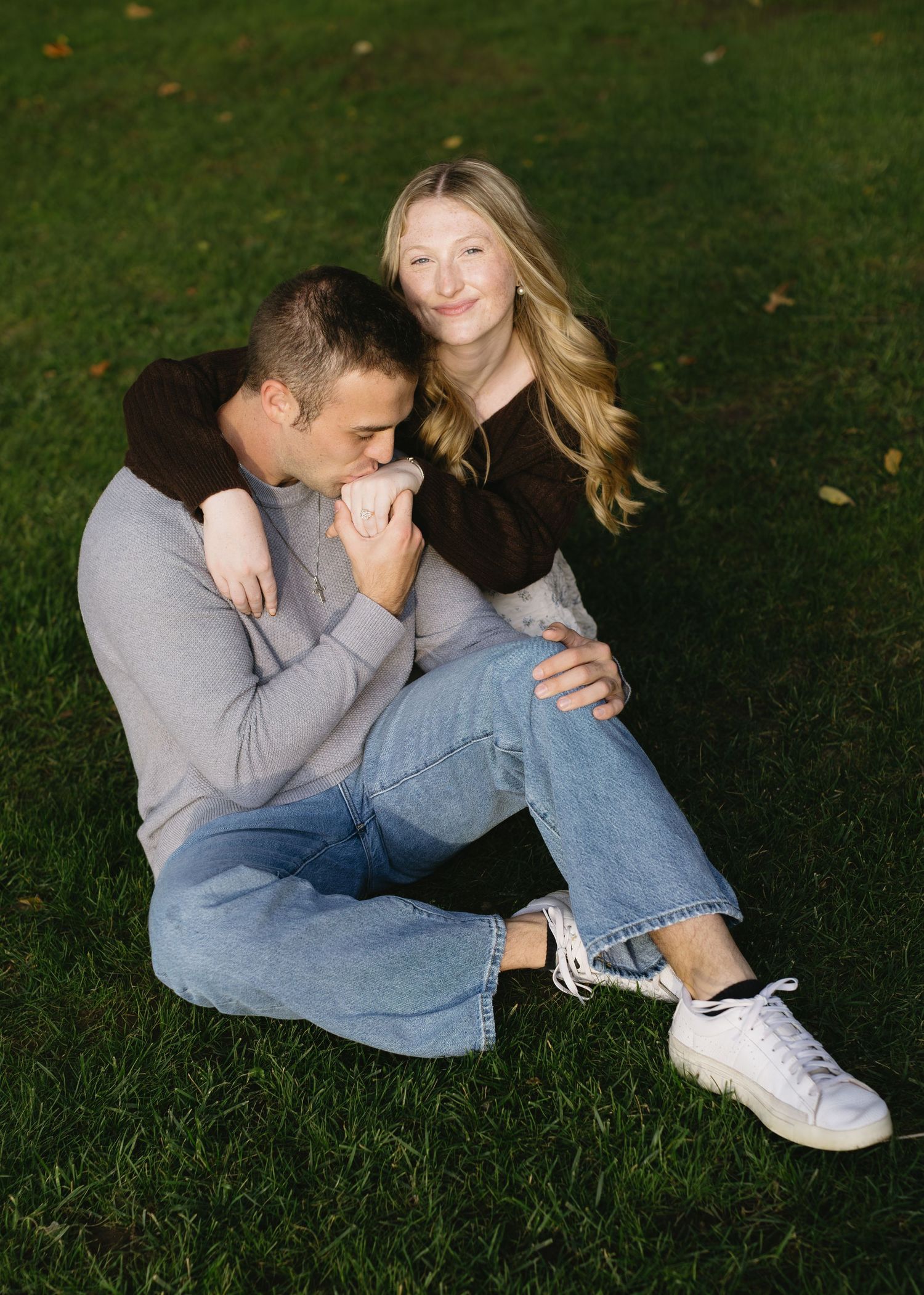 Couple relaxing together on grass during outdoor photoshoot.