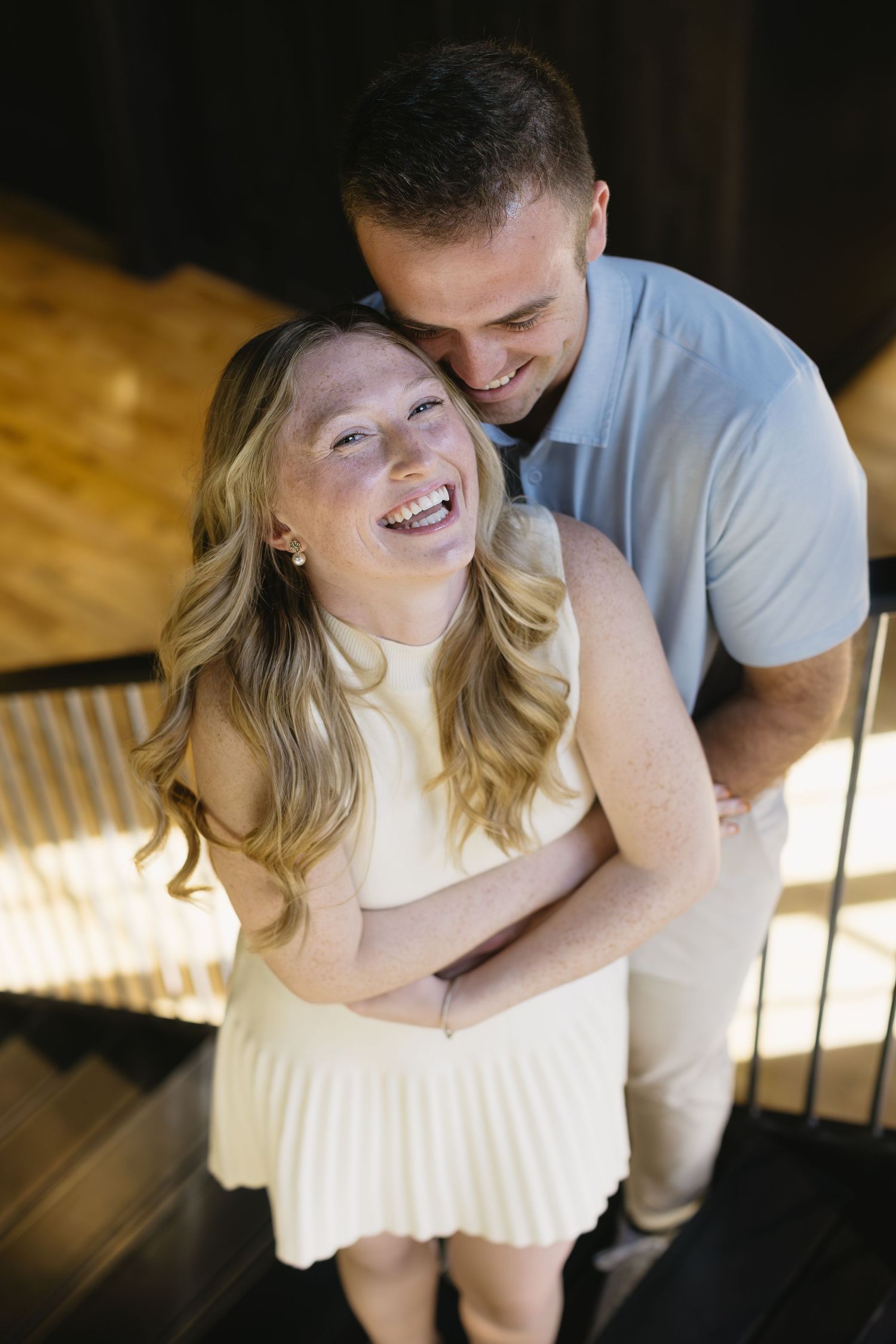 A couple shares a romantic moment together while sitting on a white bench in a dimly lit setting.