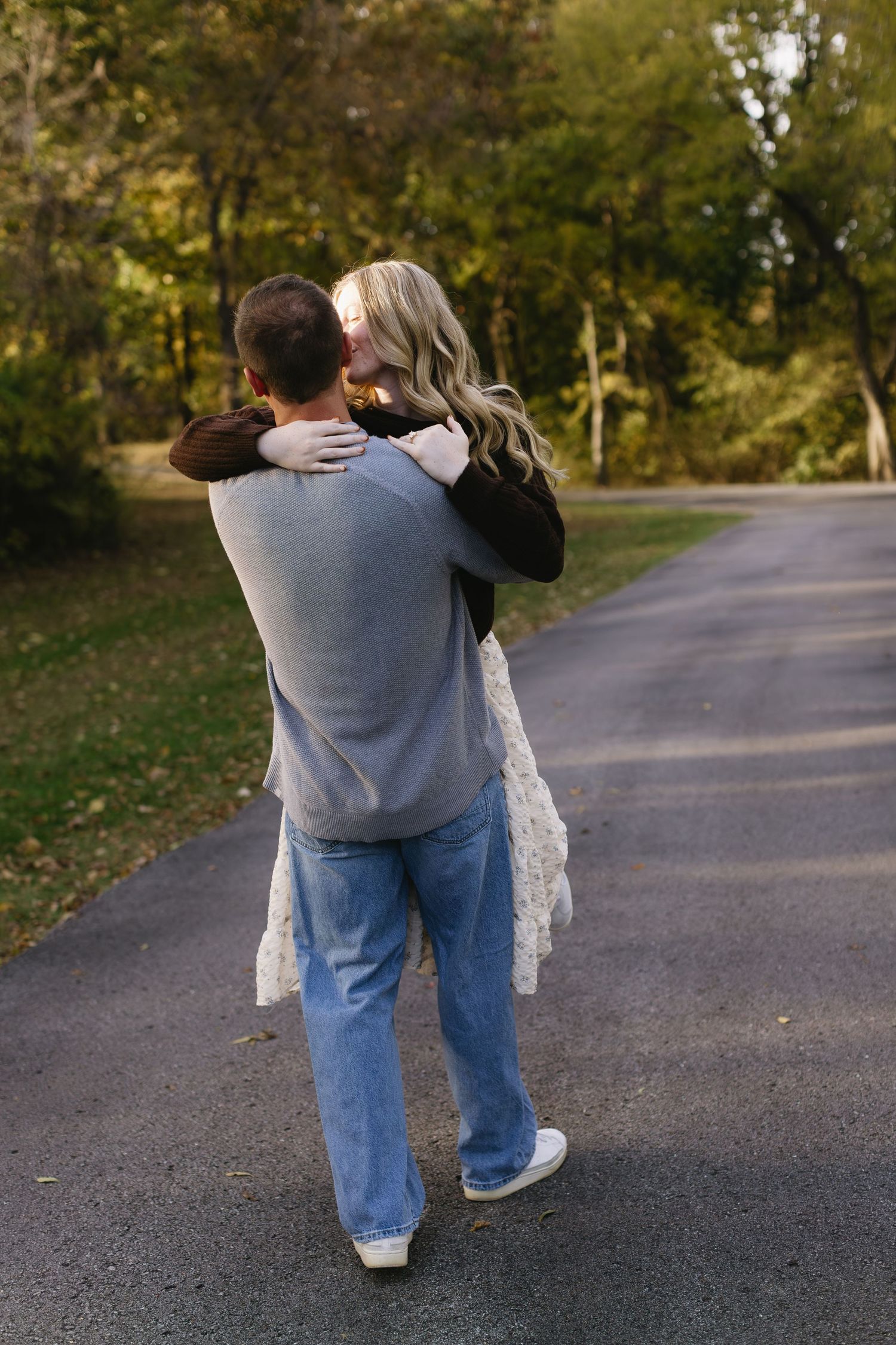 A series of photos showing a couple embracing on a paved path surrounded by fall foliage.