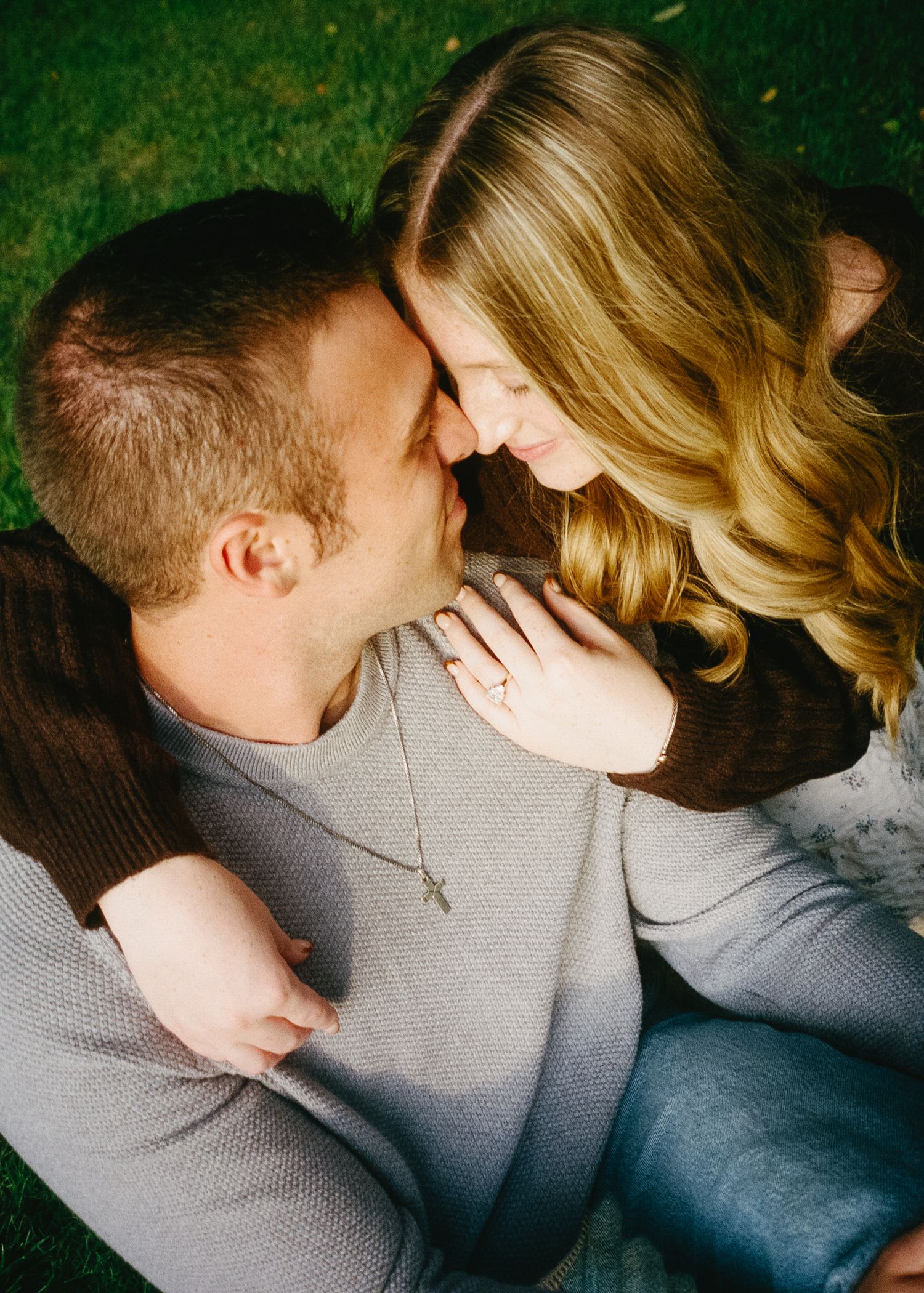 A couple shares intimate moments together while wearing matching grey sweaters in a close-up photoshoot.