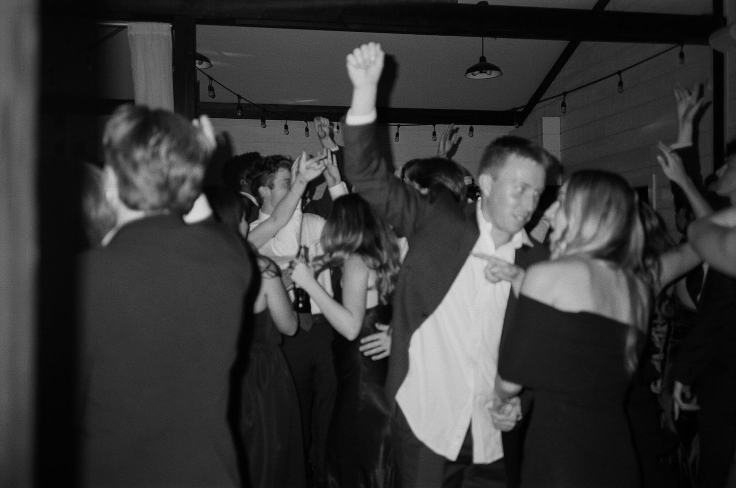 Wedding guests dancing and celebrating in black and white on the dance floor.