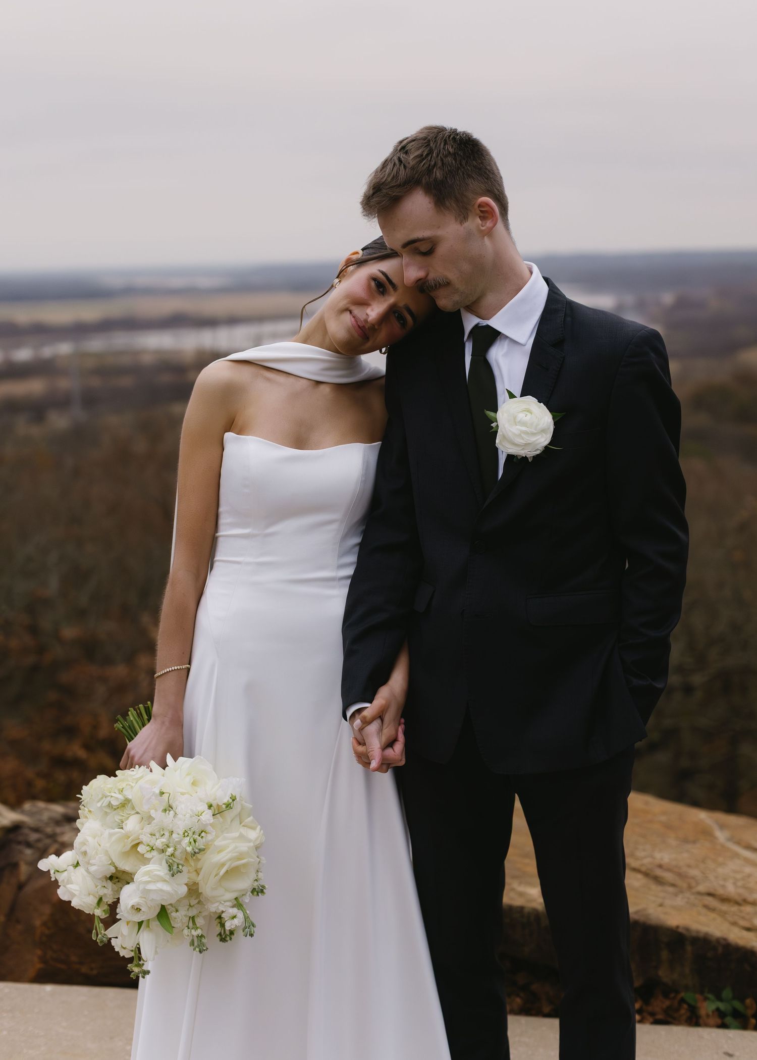 Intimate wedding portrait on scenic overlook with autumn landscape.