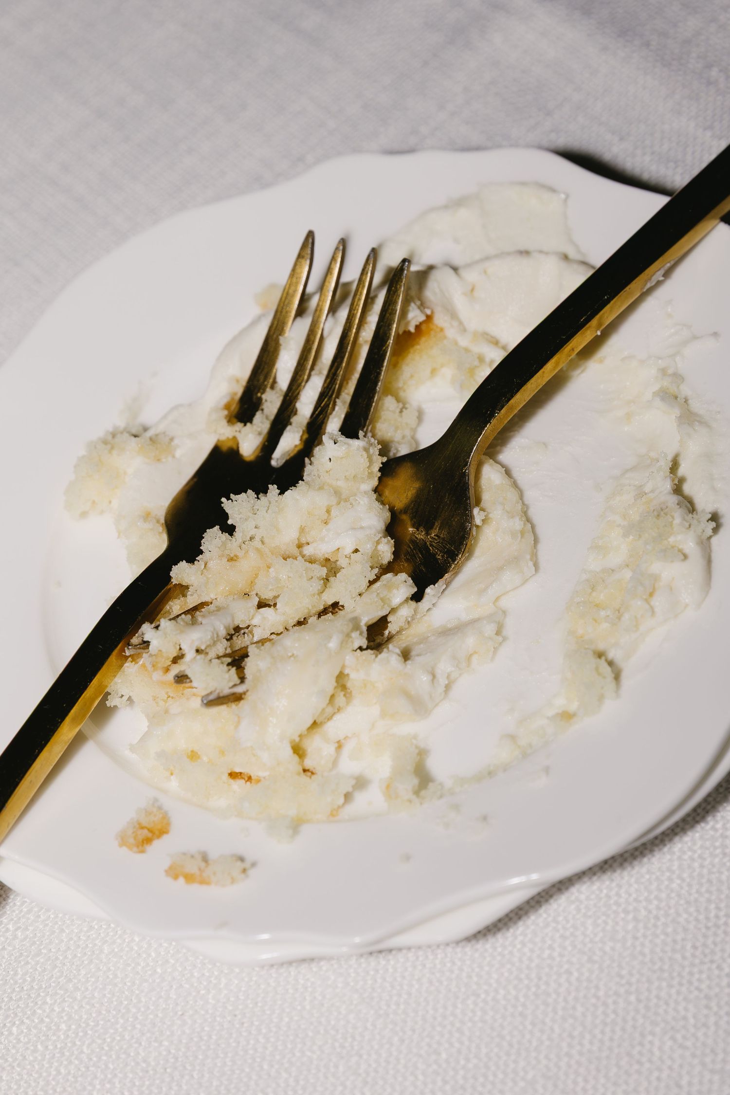 A used plate with golden utensils showing remnants of wedding cake.