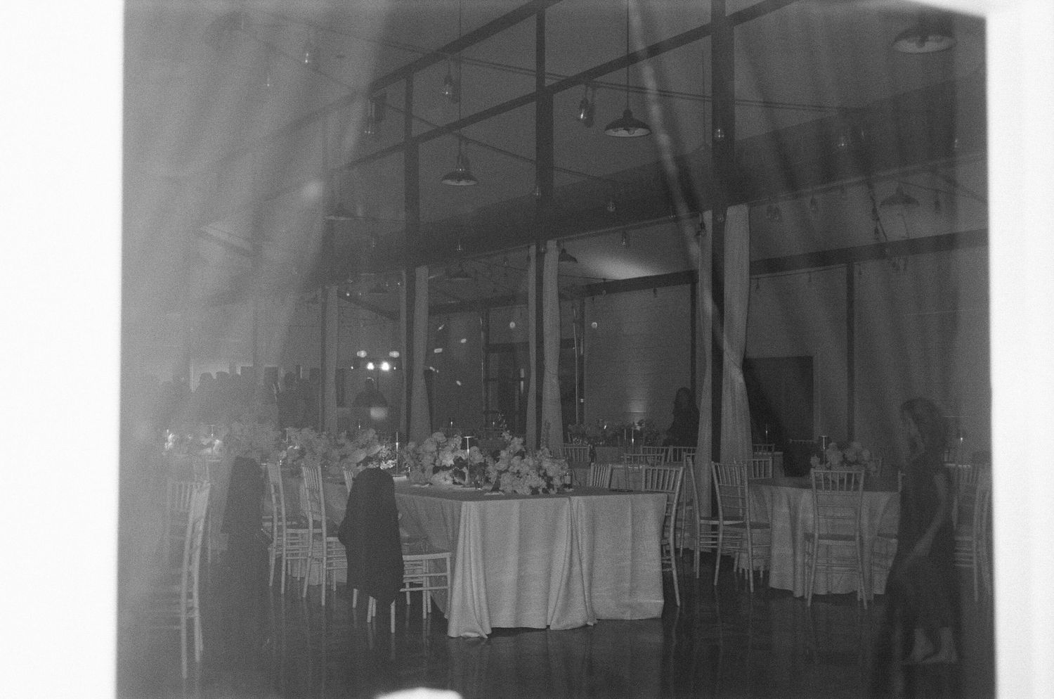 Grayscale panoramic view of an indoor wedding reception venue setup.