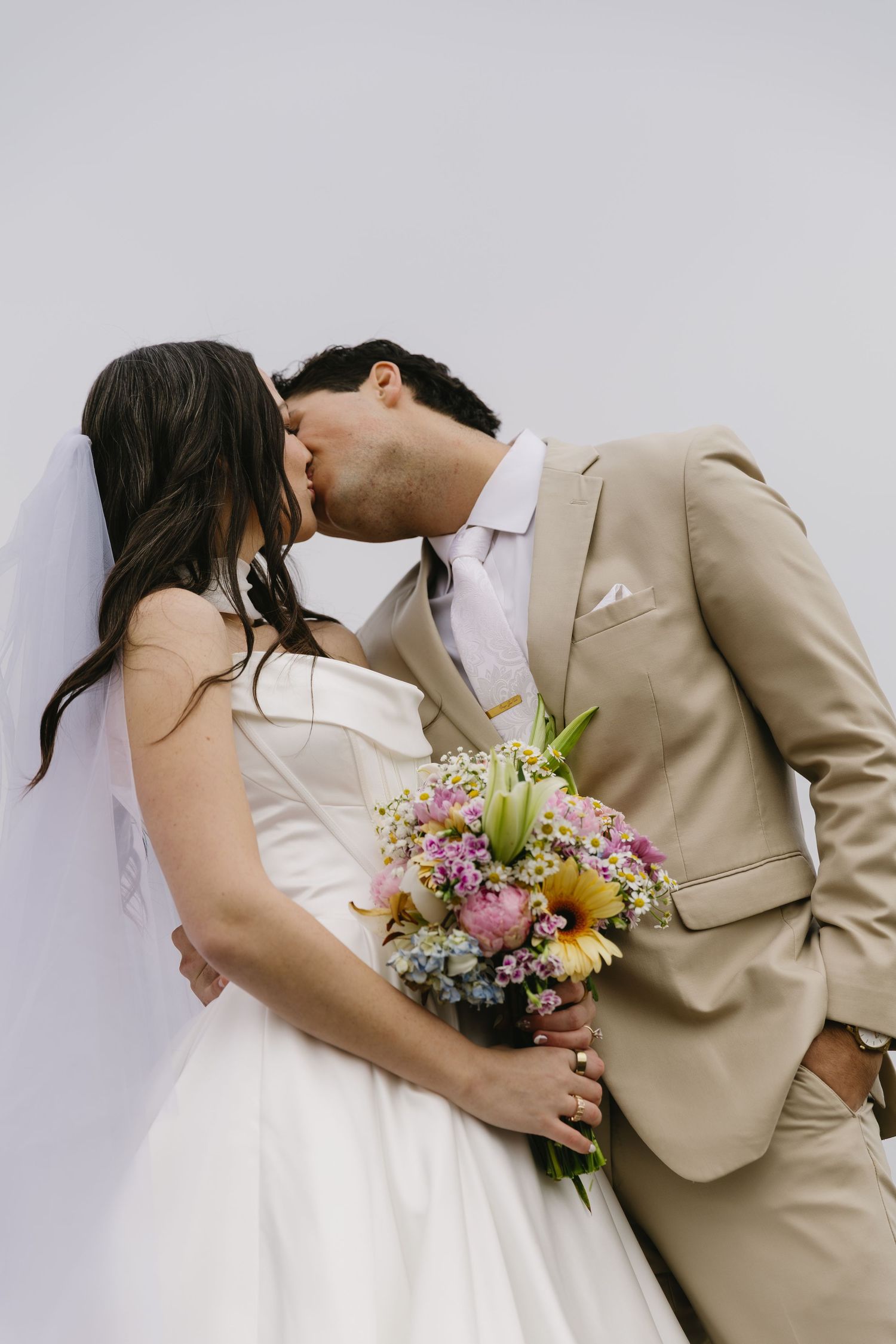 A romantic wedding photo sequence showing a couple in beige and white with a colorful bouquet sharing intimate moments.