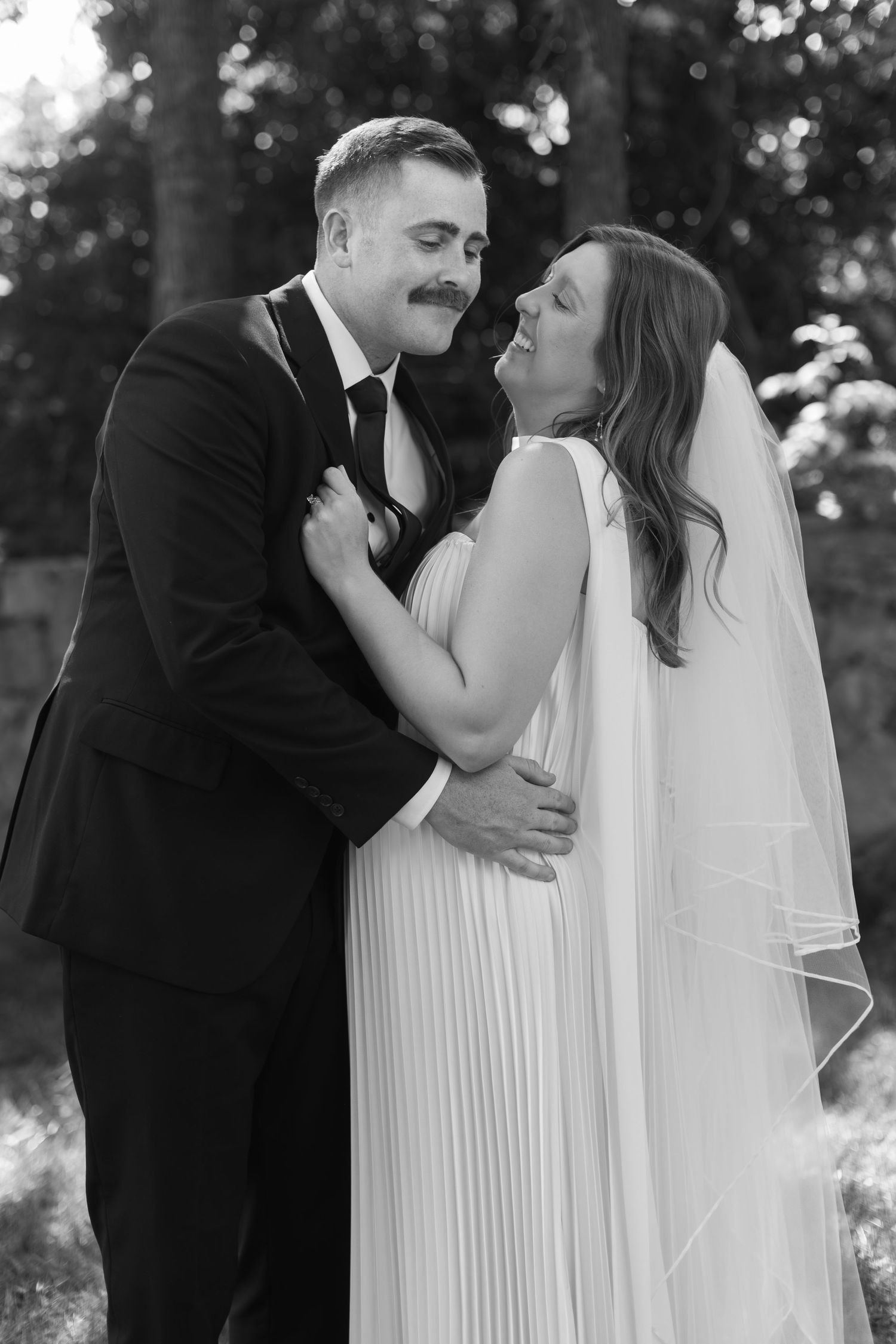 Black and white wedding photo series showing a romantic moment between a couple in formal attire.