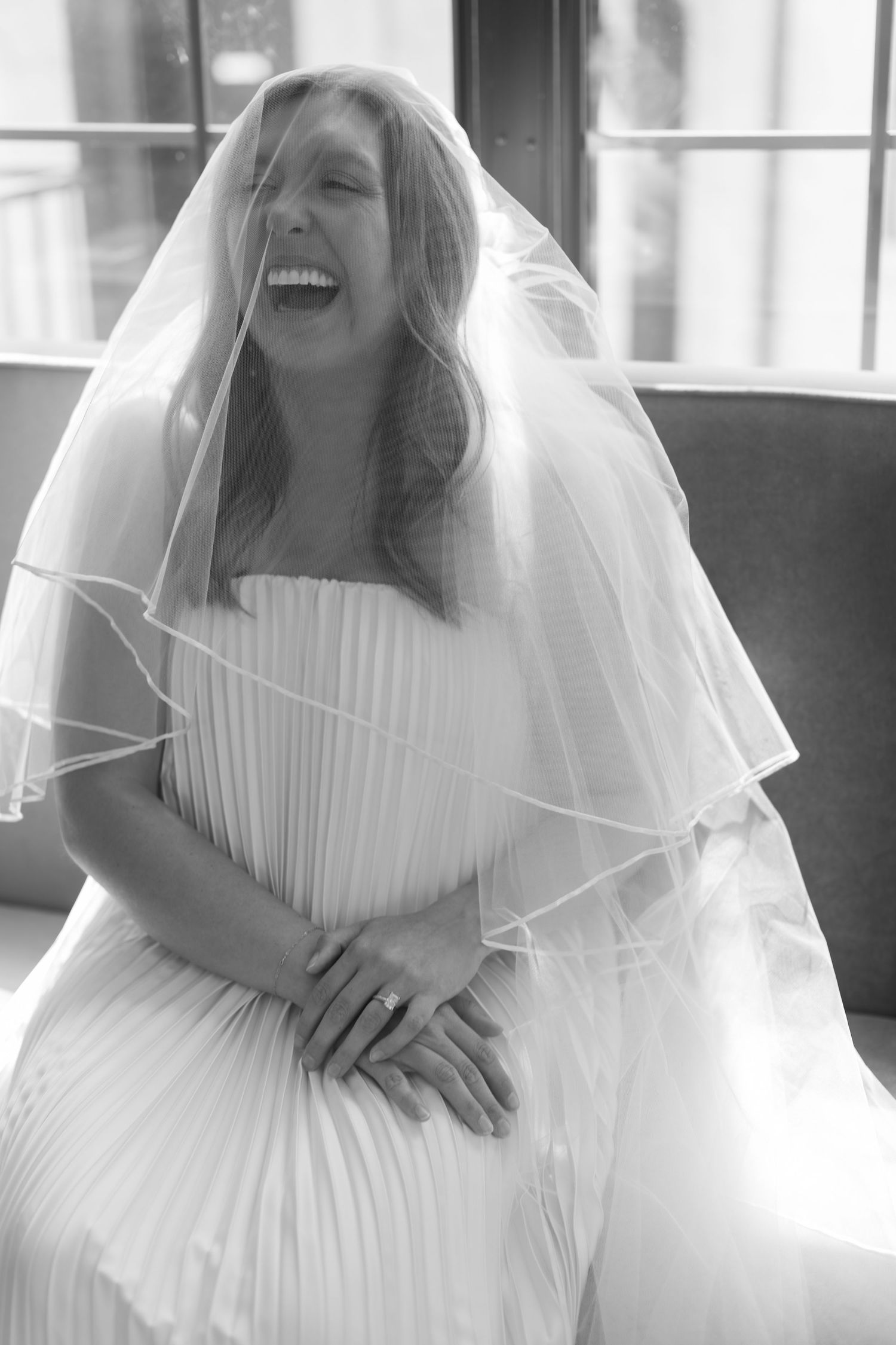 Joyful moments captured in black and white showing bride in pleated wedding dress and veil.
