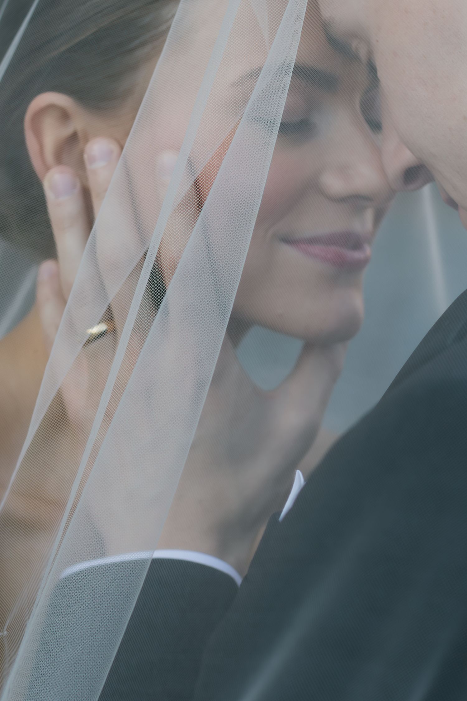 Ethereal wedding veil draping softly over a couple during an intimate moment.