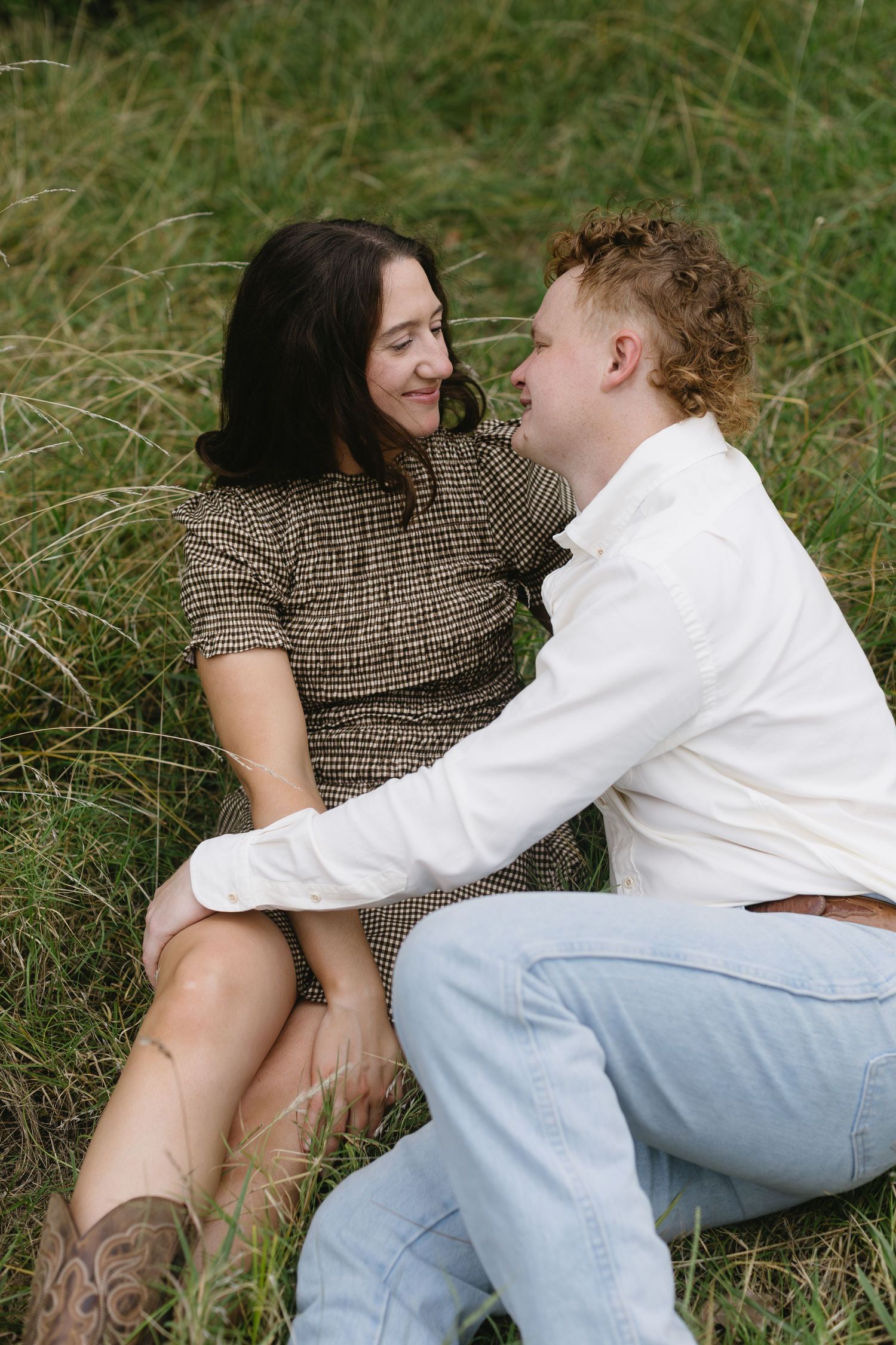 Romantic moment captured of couple laying in grass field sharing tender moments.