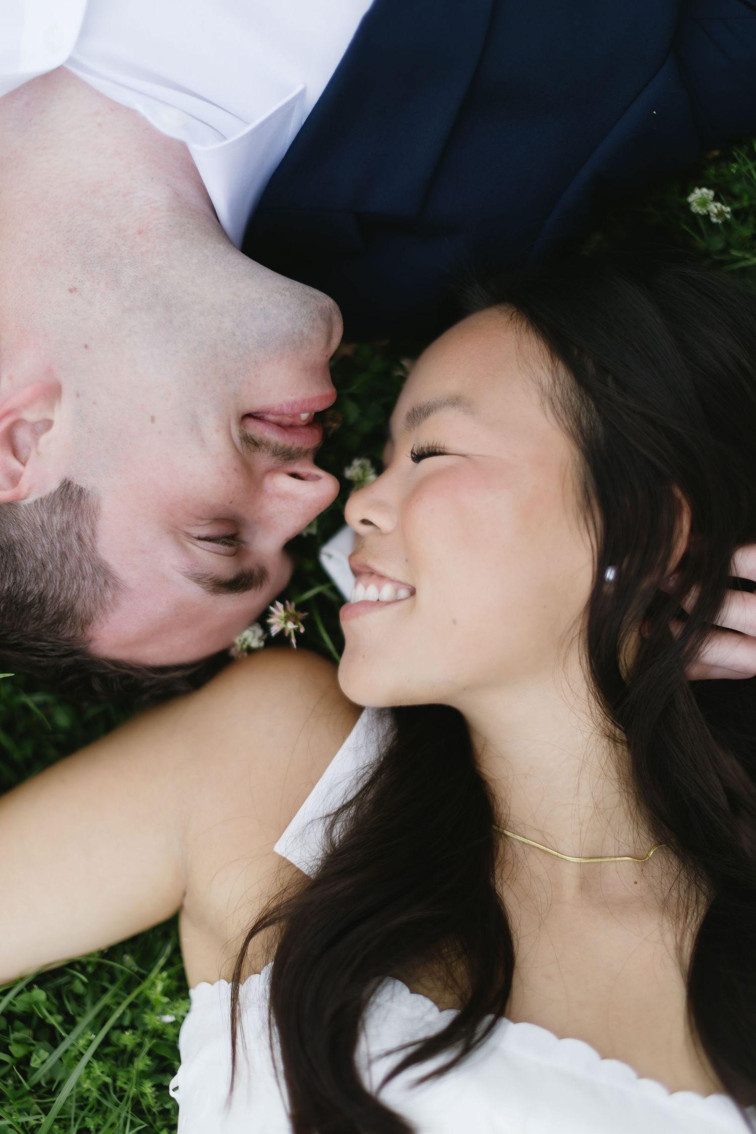 Close-up series shows intimate moments between couple lying in grass during outdoor photo session.
